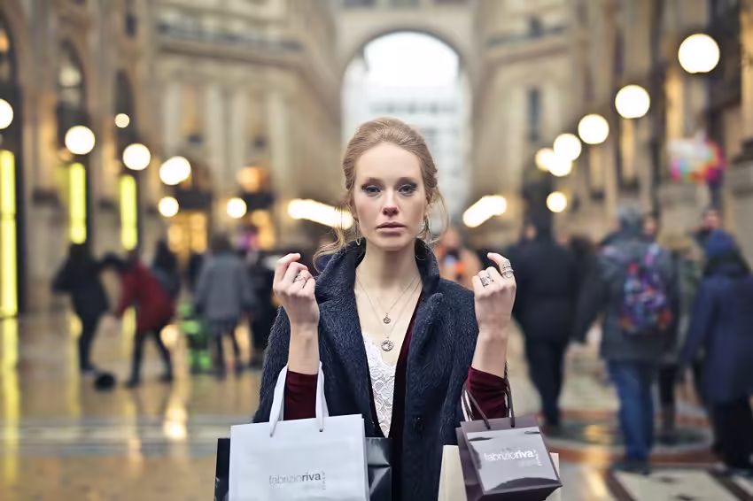 Woman holding shopping bags stands in Galleria Vittorio Emanuele II, Milan.