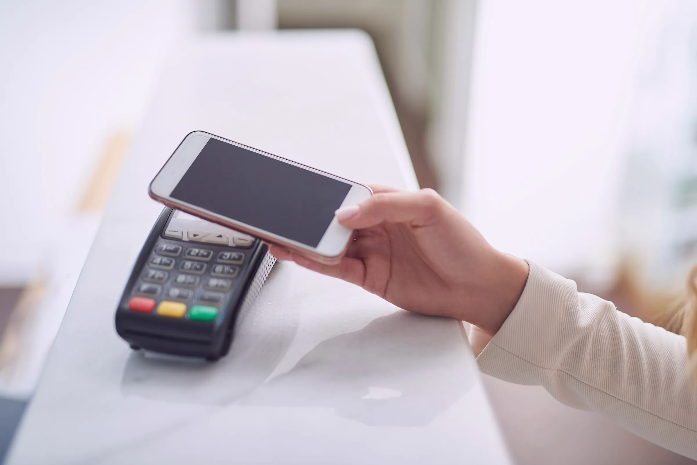 Photo d'un paiement sans contact par smartphone sur un terminal de paiement.