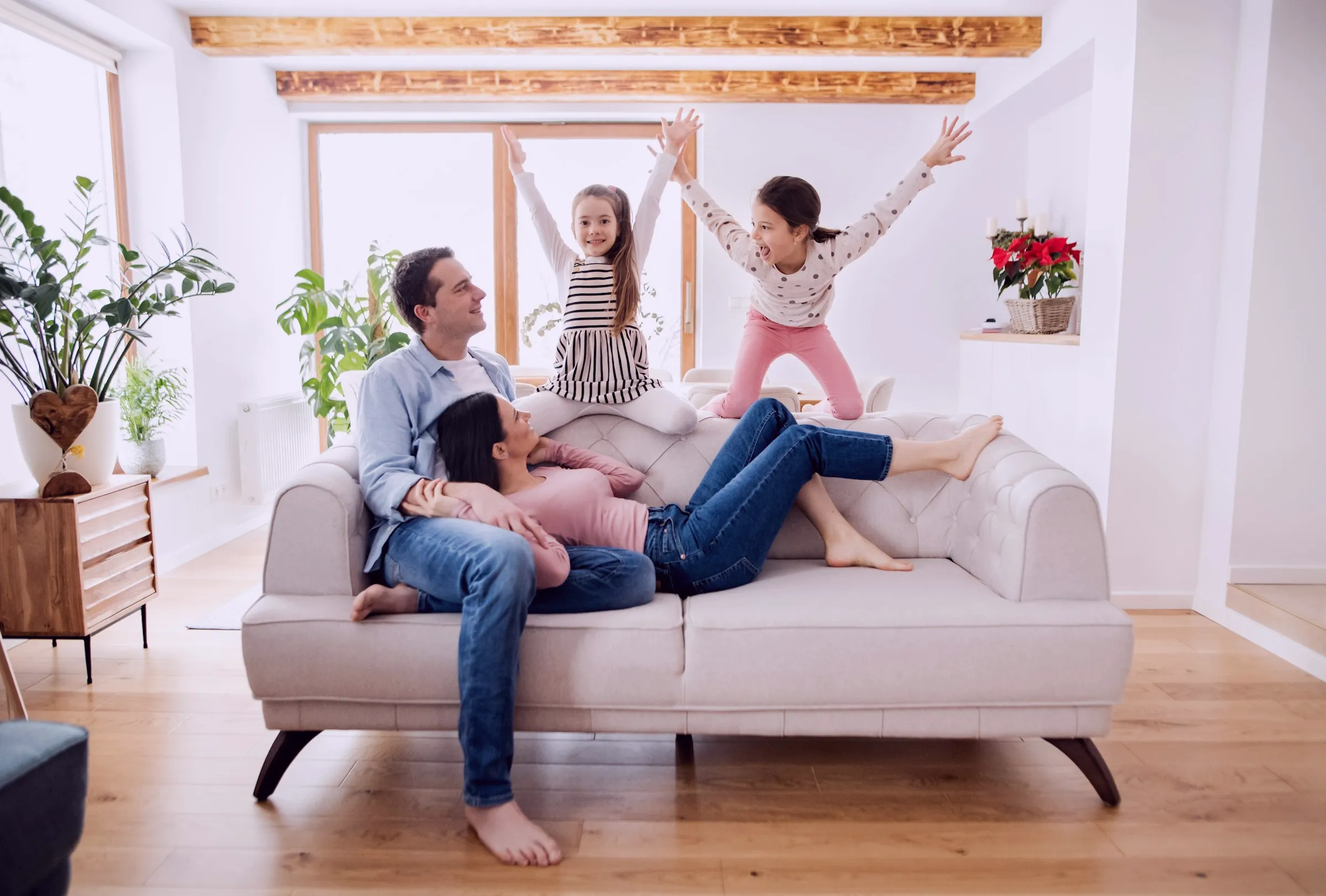 Photo of a happy family playing on the sofa in a bright living room.