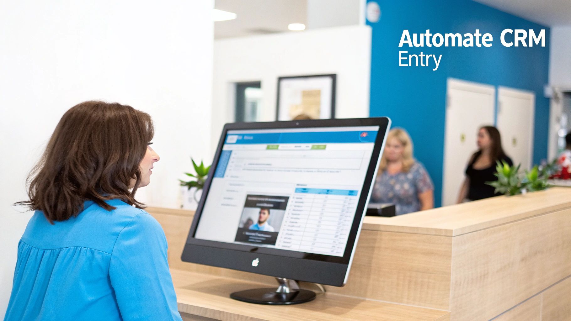 A woman looks at a computer screen displaying a CRM application at a reception desk.
