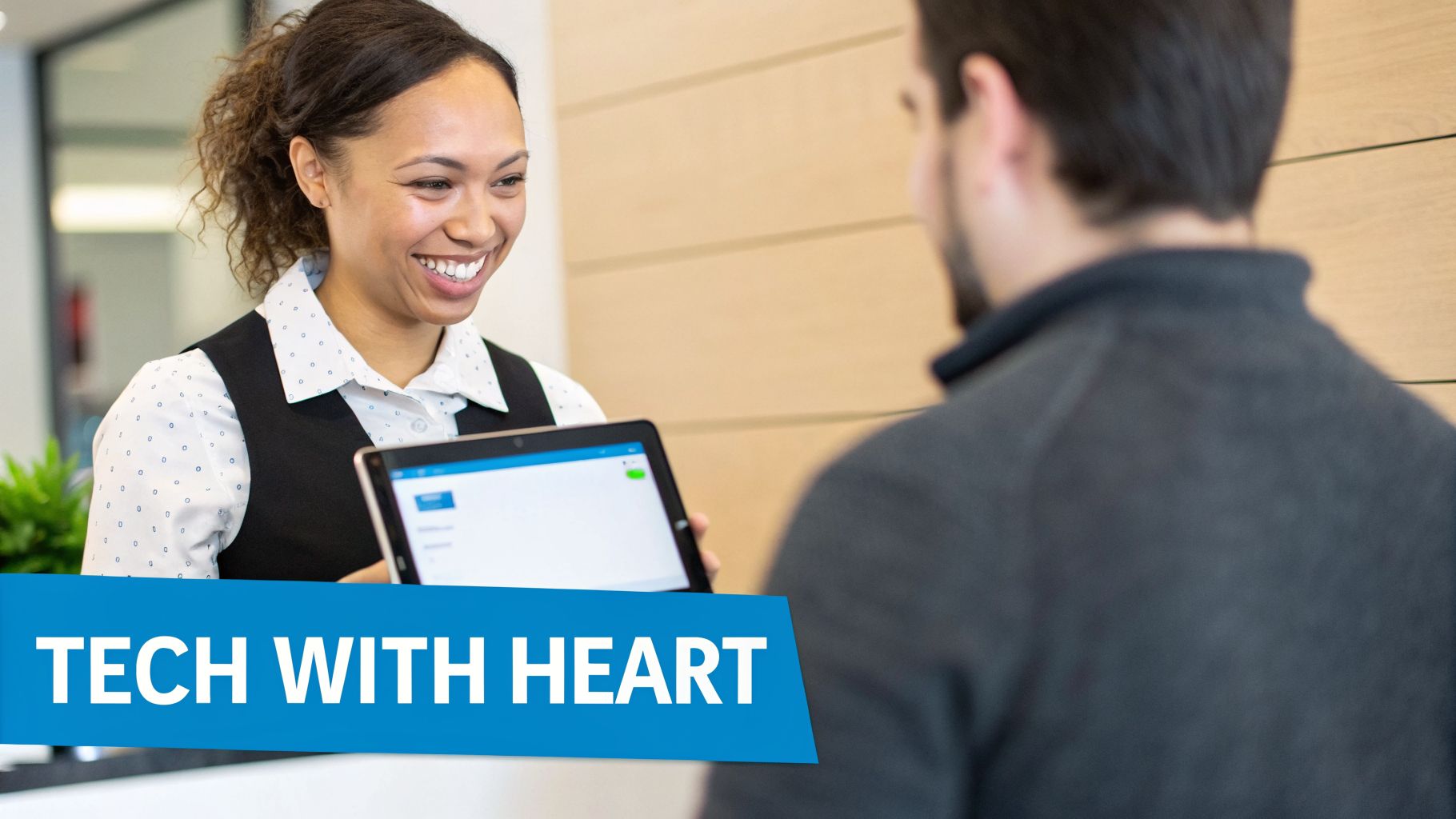 A smiling woman in a vest holds a tablet, interacting with a customer, representing tech with heart.