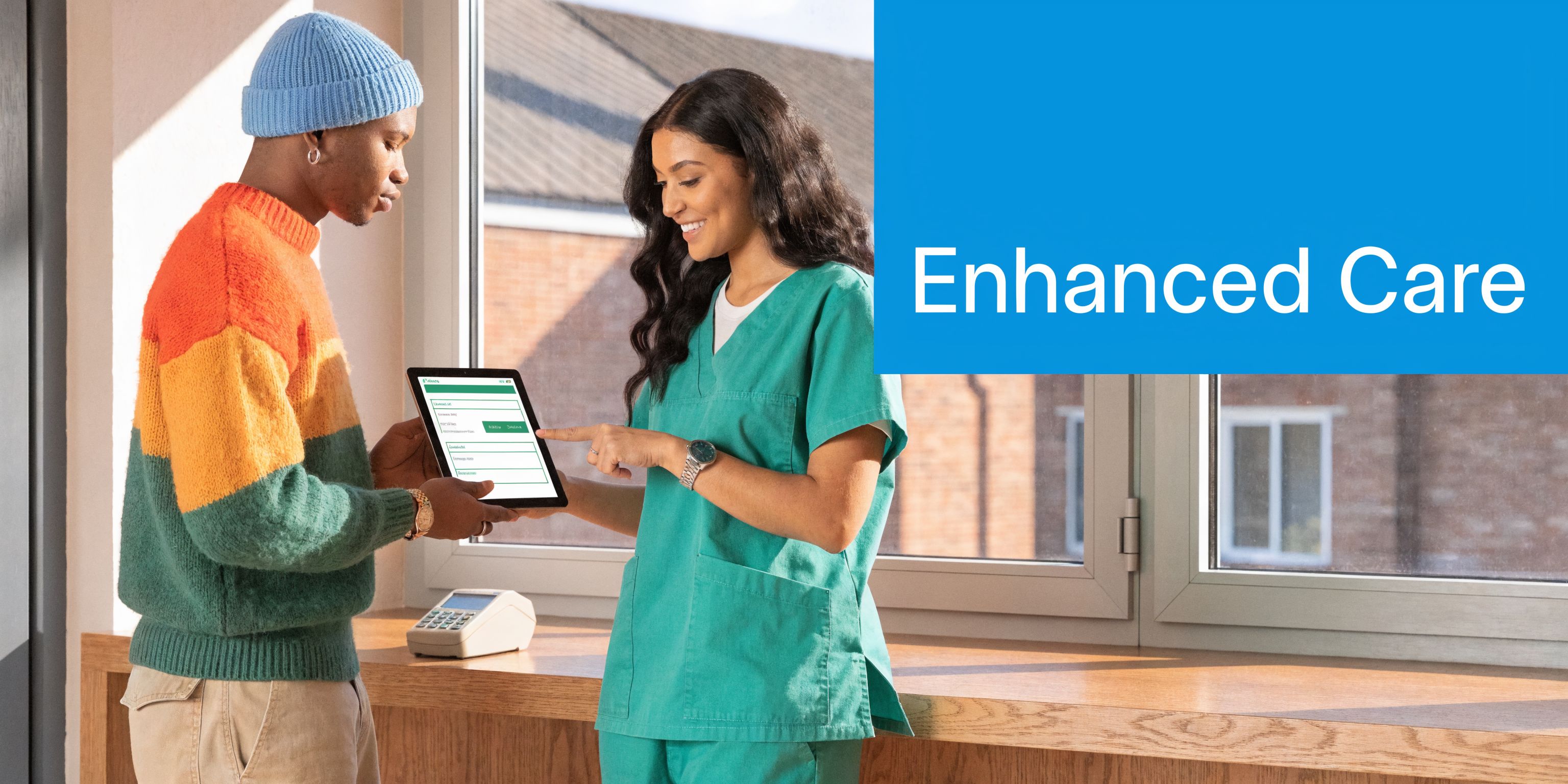 A healthcare worker in green scrubs helping a patient with digital tablet scheduling in a bright office.
