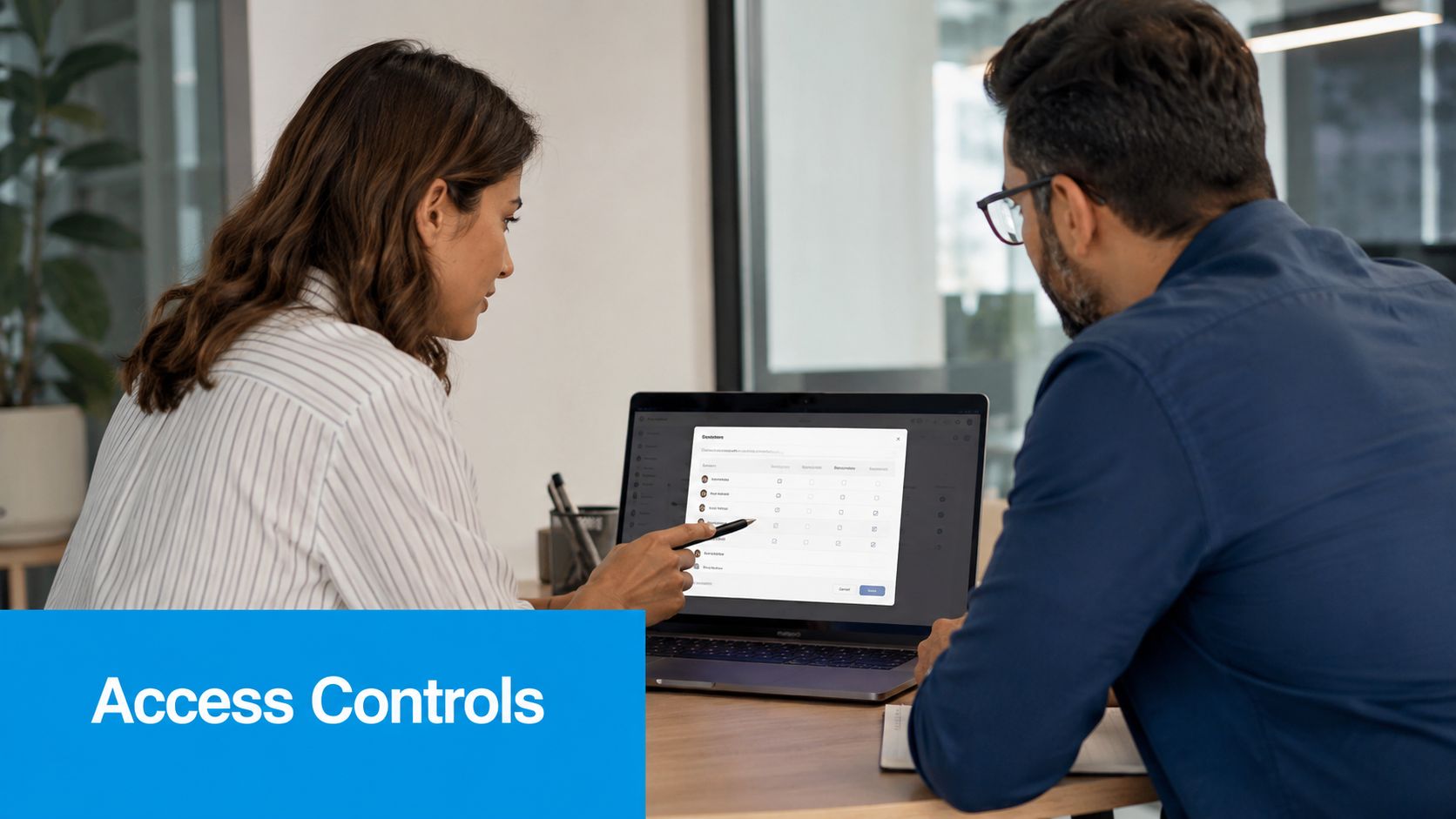 A professional woman explaining security permissions on a laptop screen to a colleague in an office setting.