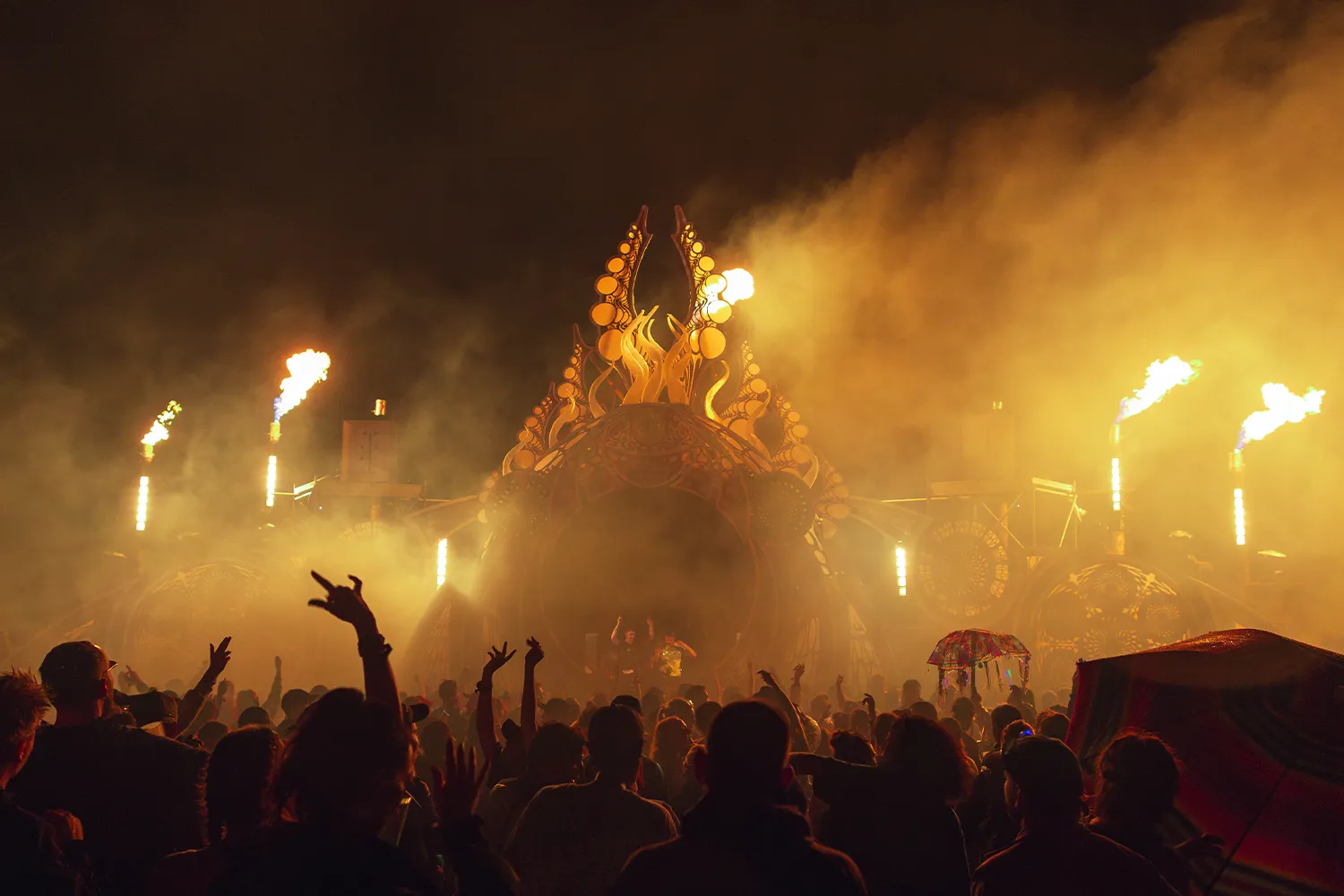 Eine tanzende Menge vor einer Bühne, auf der Flammen zu sehen sind.