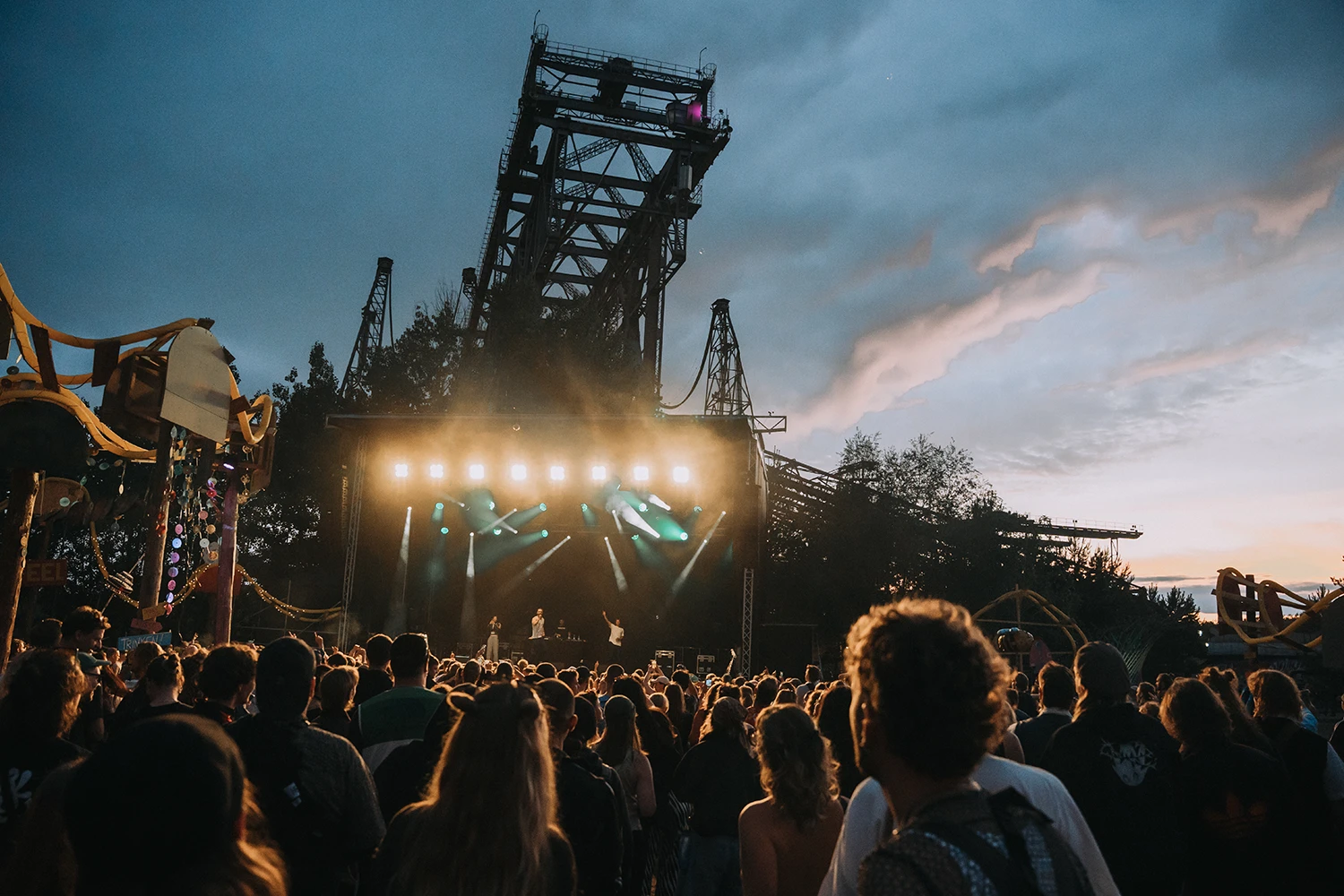 Eine Menschenmenge vor der Takraf-Bühne. Im Hintergrund ist die F60 und ein Sonnenuntergang zu sehen.