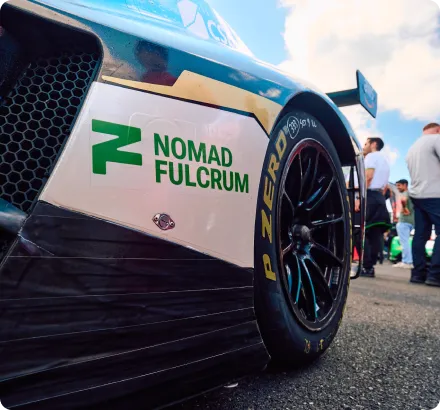 Close-up of a race car's rear wheel with Pirelli P Zero tire and Nomad Fulcrum logo on the car body.
