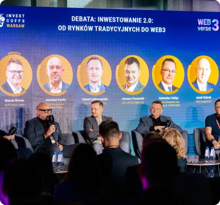 Panel discussion with five speakers seated on stage under a large screen displaying portraits and names of six speakers for a debate on investing from traditional markets to Web3.