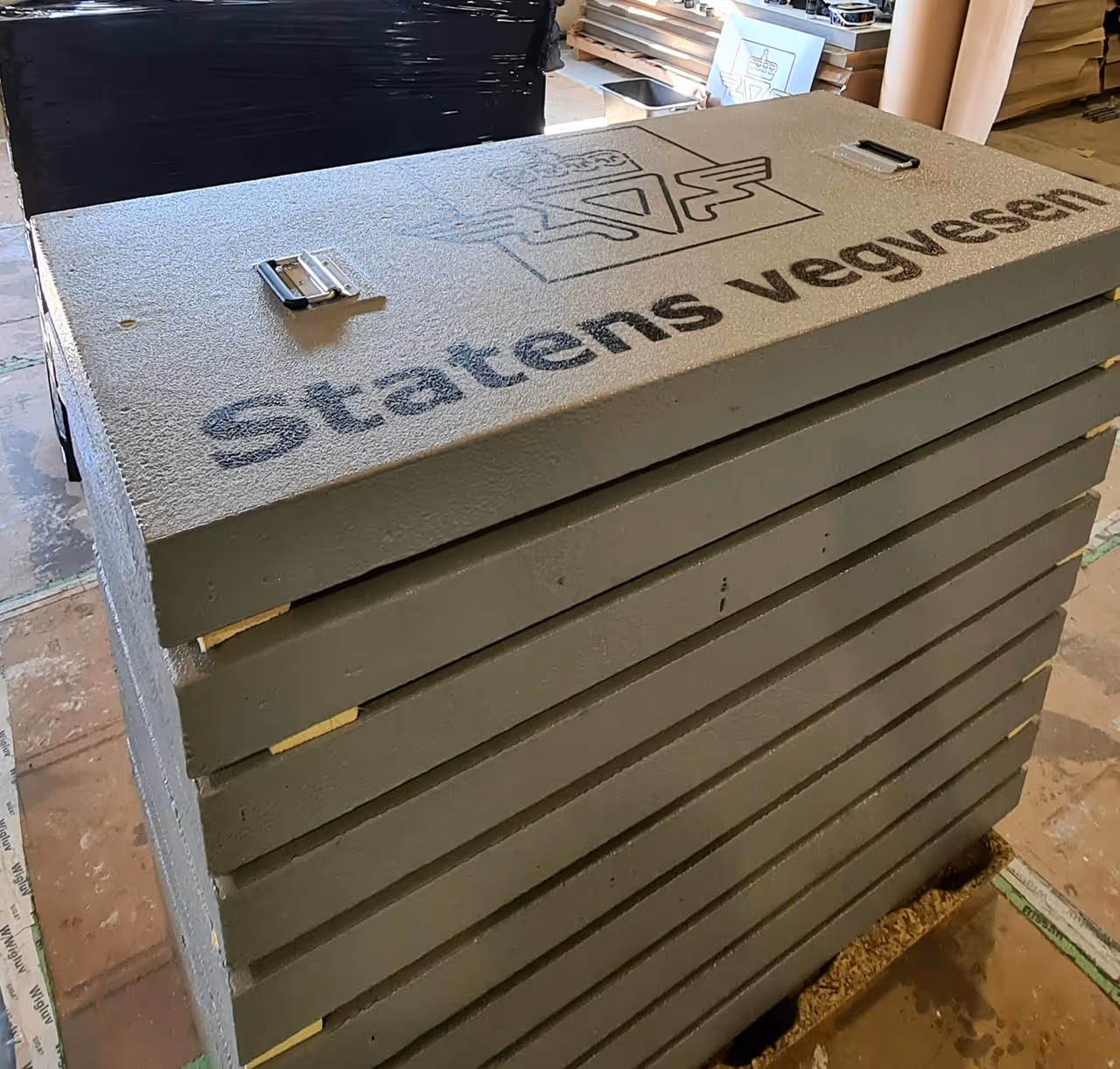 Stable, grå betonglokker med teksten 'Statens vegvesen' og logo stablet på hverandre.
