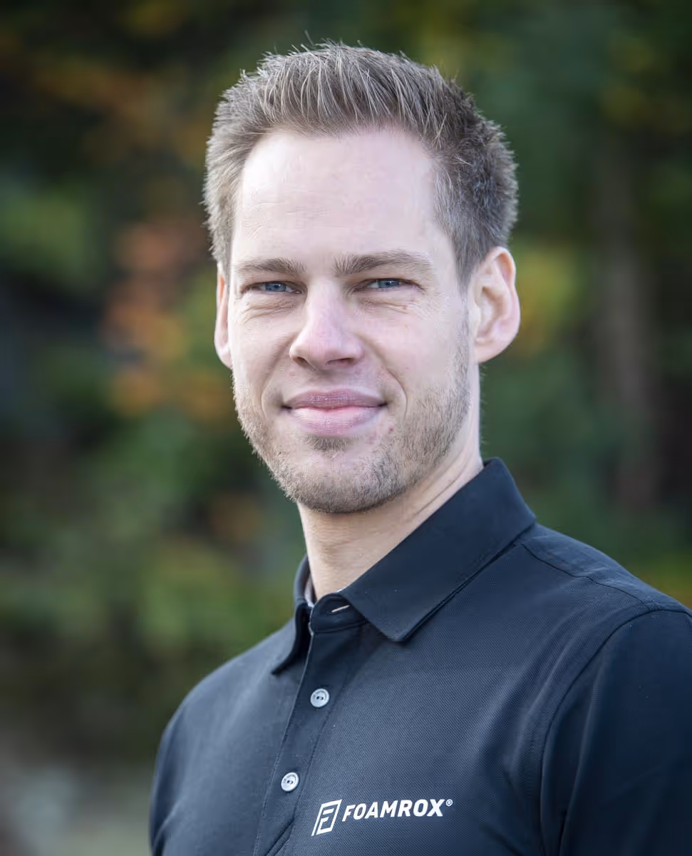 Portrett av en mann i svart Foamrox poloshirt utendørs med uskarp grønn bakgrunn.