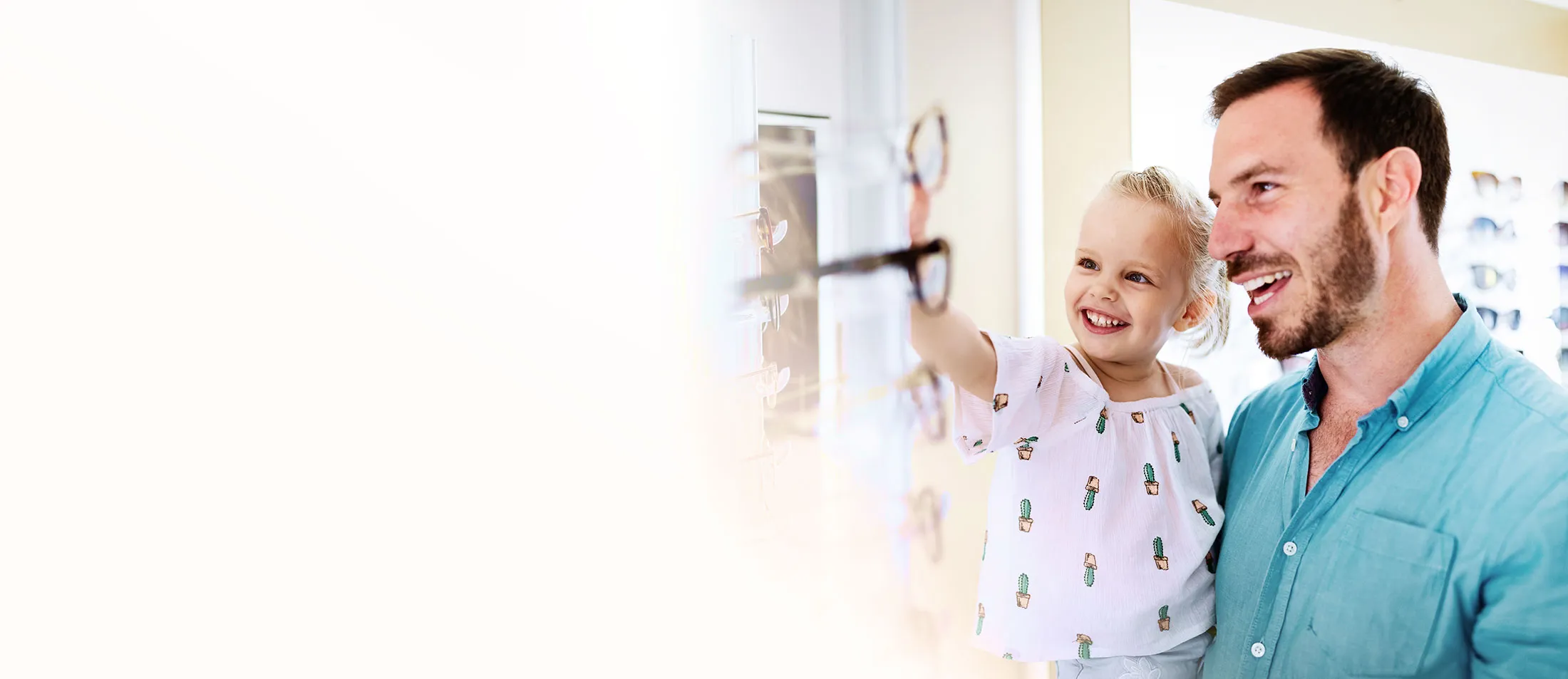 Smiling child and parent choosing glasses in an optician shop