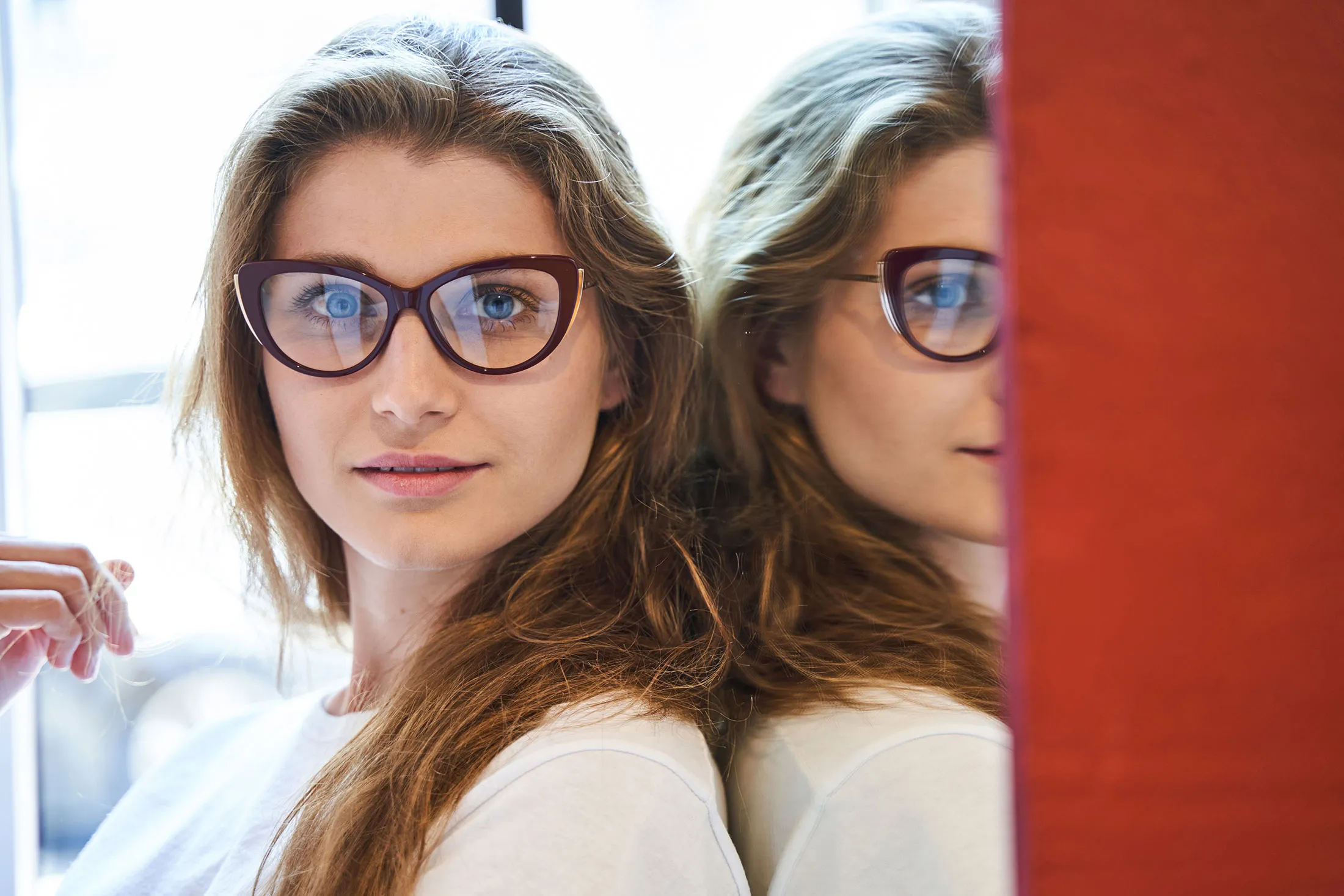 Woman with glasses standing near mirror reflecting her profile