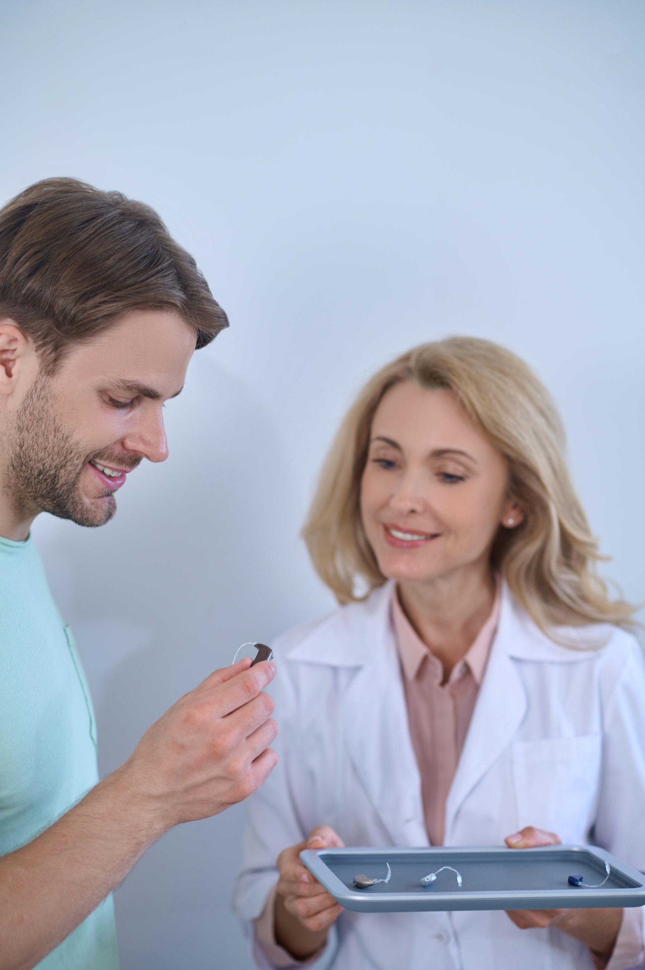 Medical professional showing hearing aid to patient during consultation