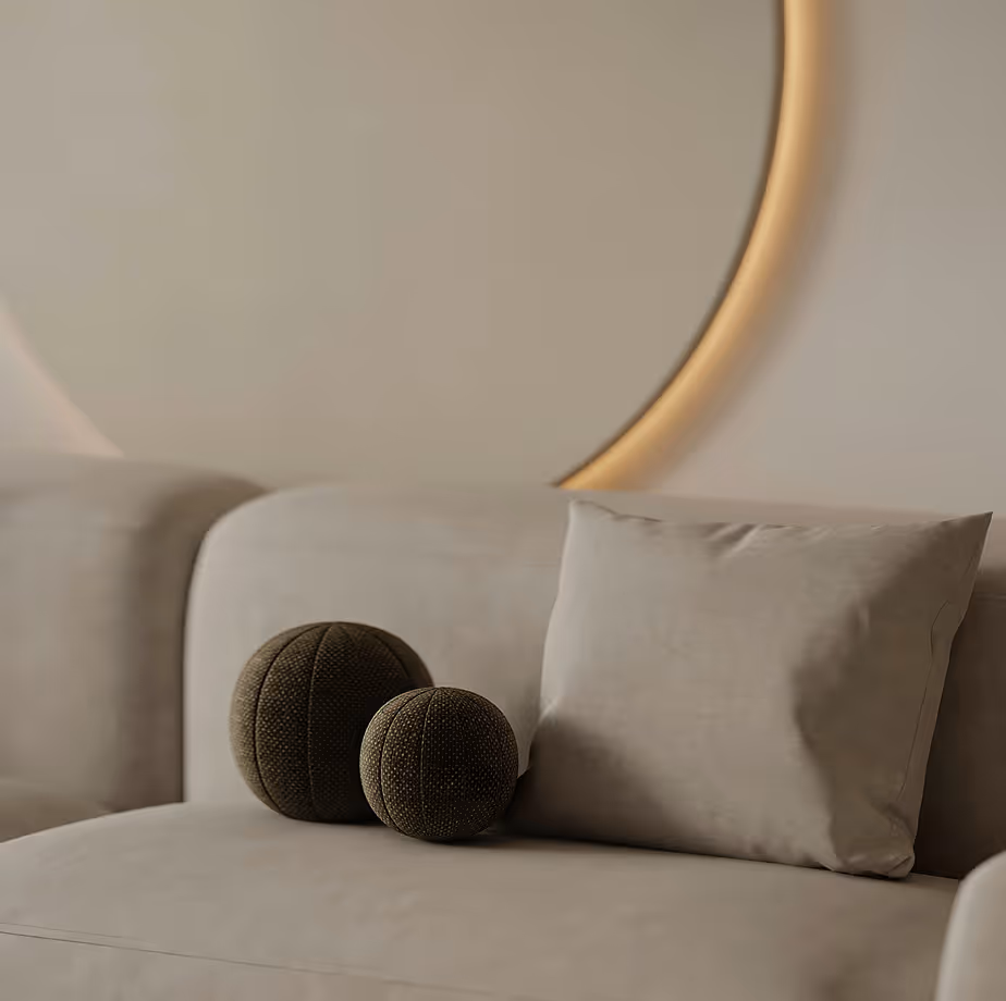 Two textured decorative balls and a beige pillow on a beige sofa under a round wall mirror.