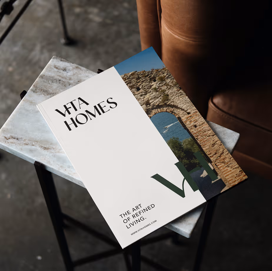 Vita Homes brochure on a marble table with a stone arch photo and text about refined living.