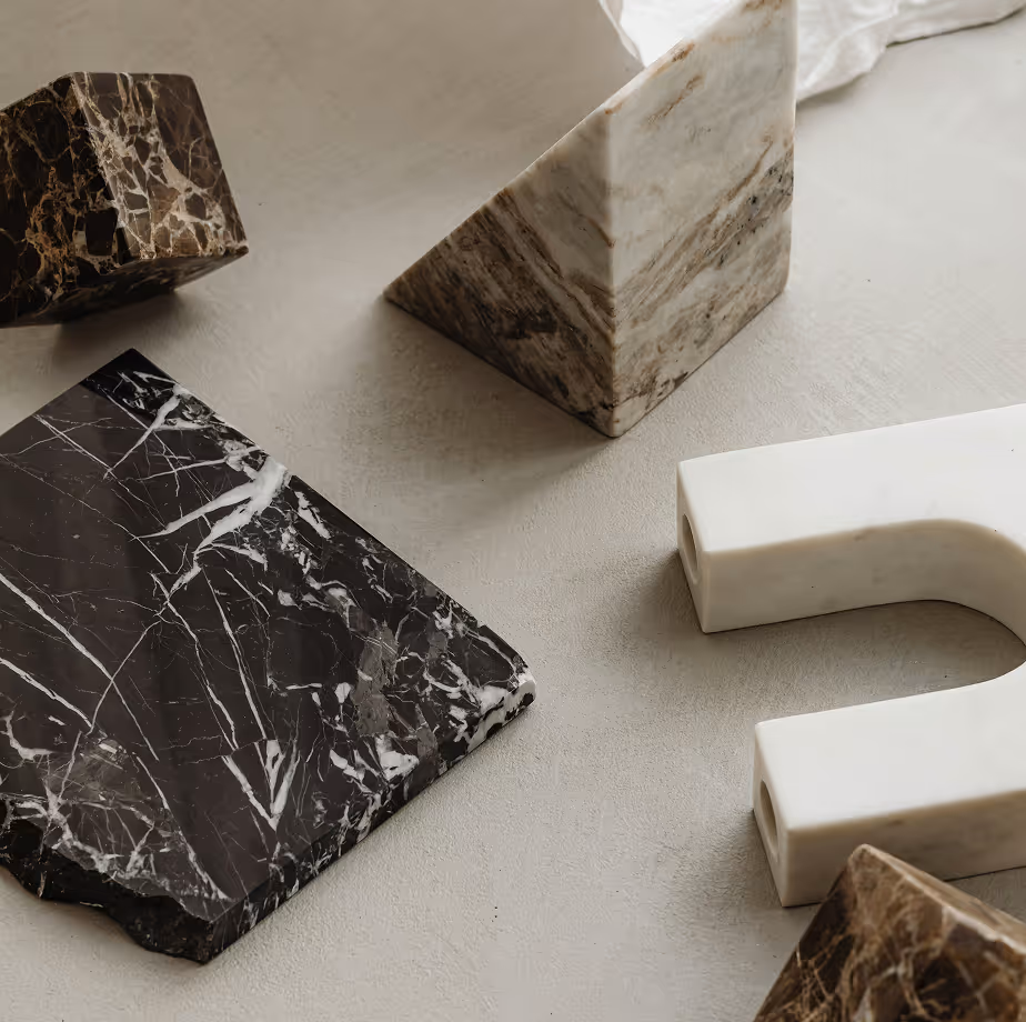 Assorted geometric marble shapes including a pyramid, arch, and slabs in various colors on a surface.