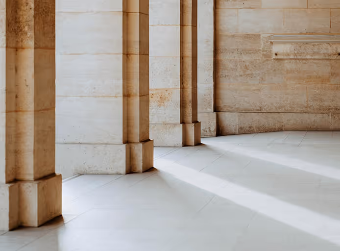 Light streaming through columns casting long shadows on a smooth stone floor and wall.