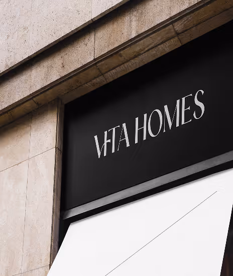 Black sign with white text 'VITA HOMES' above a white awning on a building.