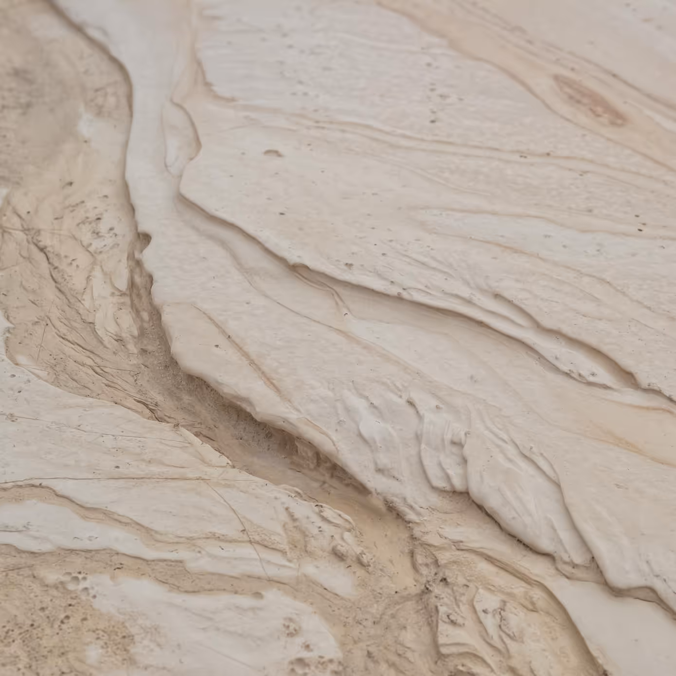 Close-up of beige marble surface with natural veins and textured patterns.