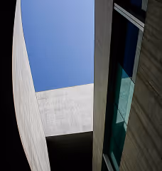 View of modern building structures with concrete walls and glass window against a clear blue sky.