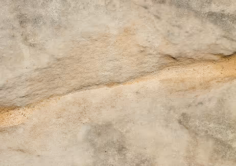Close-up of textured beige stone surface with a distinct horizontal crack.