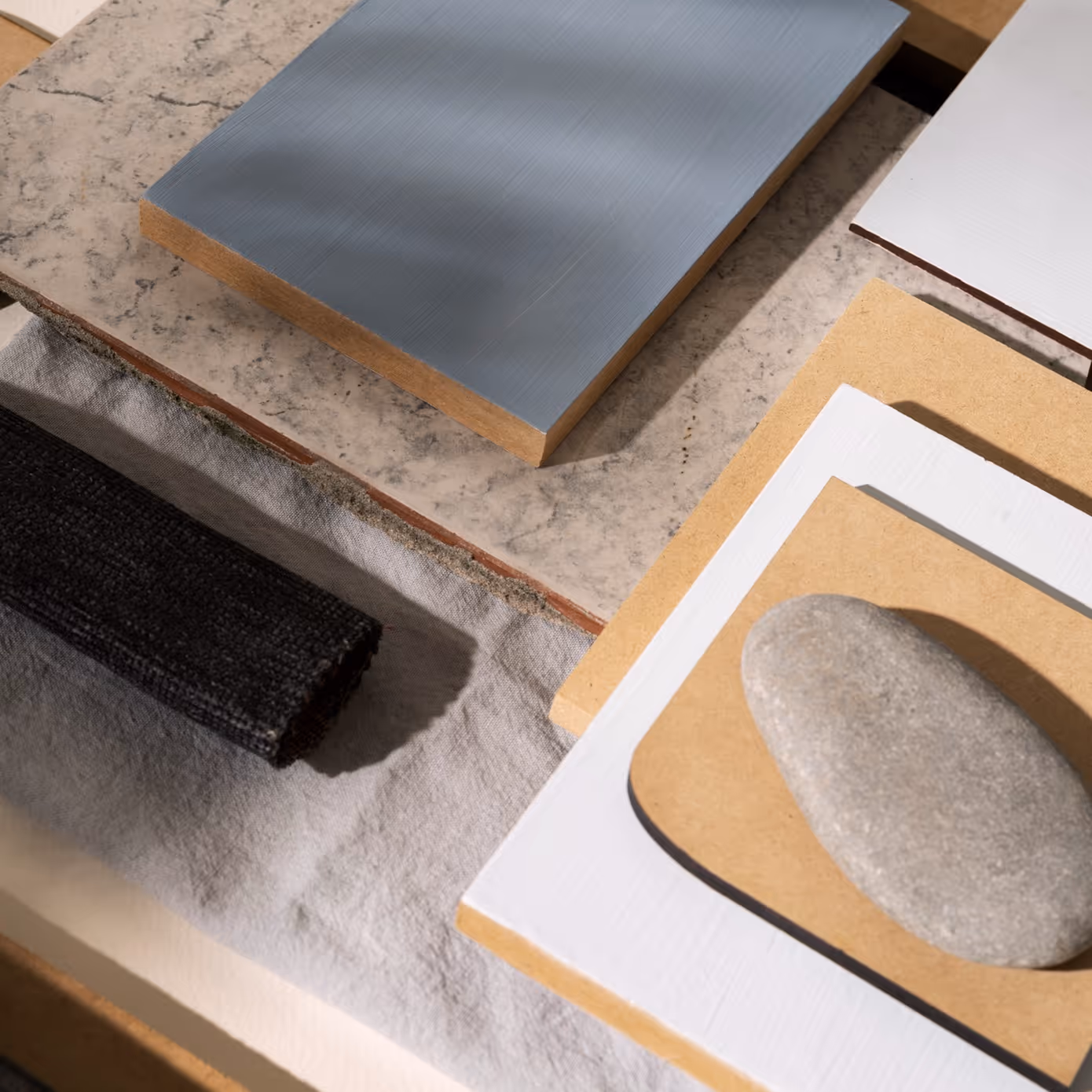 Flat lay of textured fabric, stone, wood, and tile samples in neutral and muted colors.