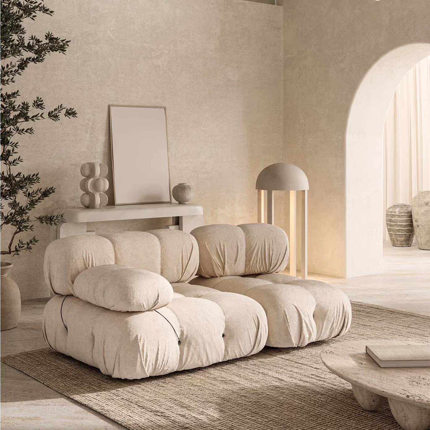 Beige modular sofa with rounded cushions on woven rug in a minimalist room with arched doorway.