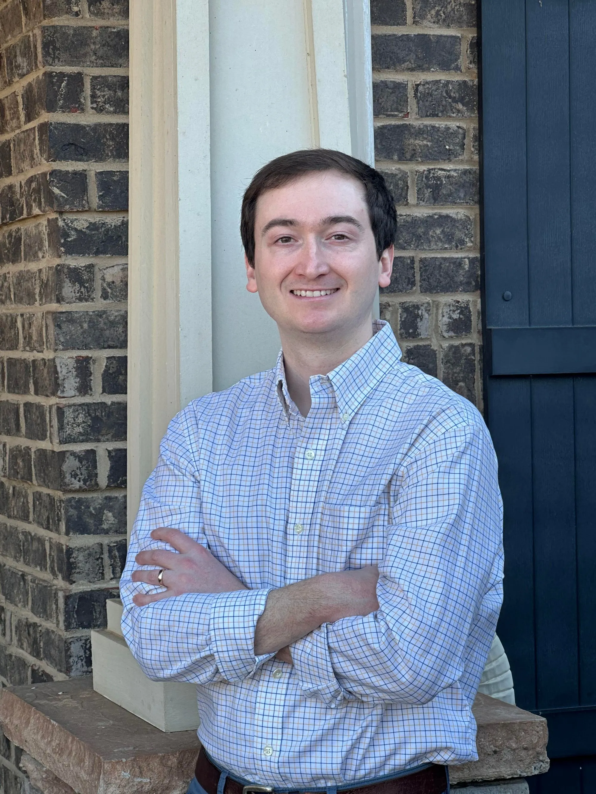 A man wearing a plaid shirt and a ring on his finger.