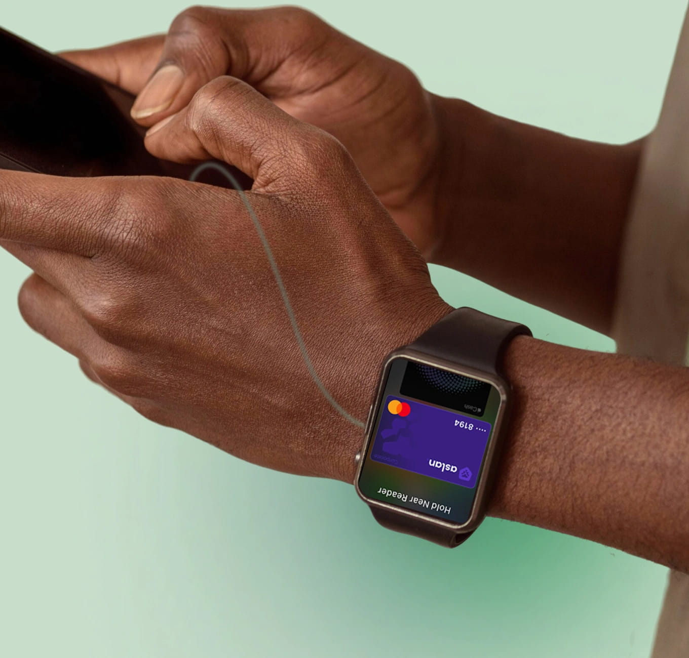 Close-up of a person holding a phone with a smartwatch displaying a digital payment card screen.