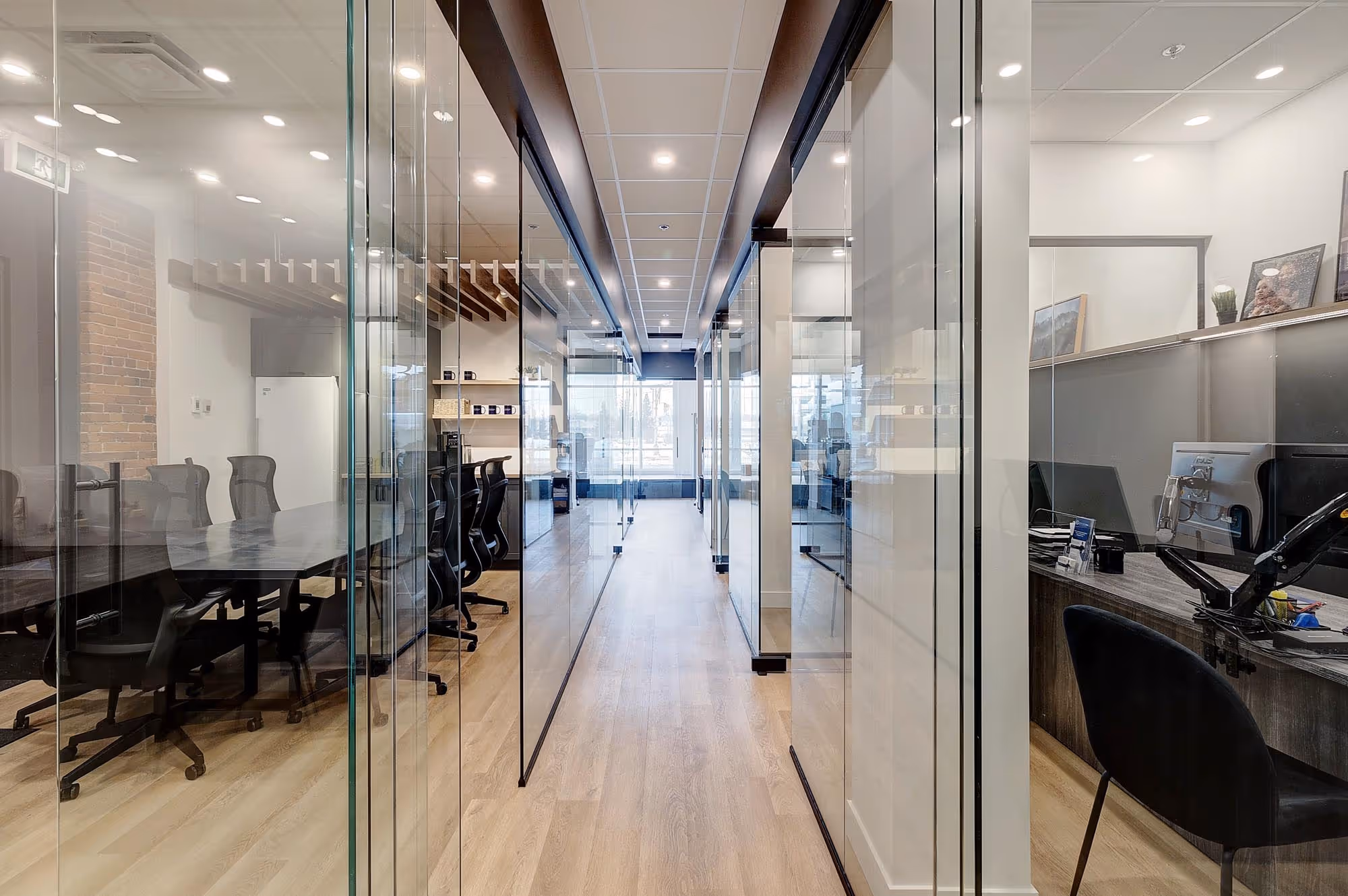Couloir lumineux dans un bureau moderne avec des salles de réunion vitrées de chaque côté.