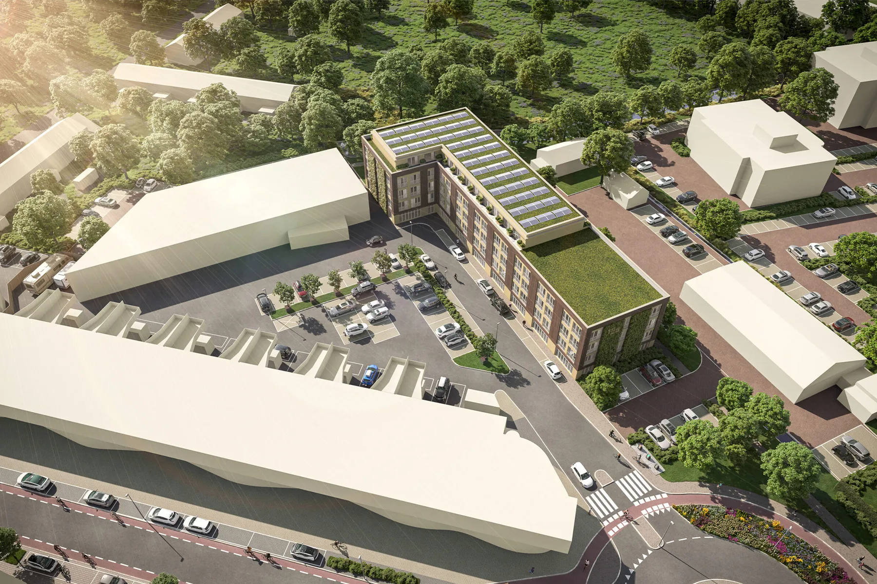 Luchtbeeld van een middelhoog woongebouw met groene daken en zonnepanelen, omringd door parkeerplaatsen, straten en bomen, gelegen in een laagbouwstedelijke omgeving naast een bosrijk gebied.