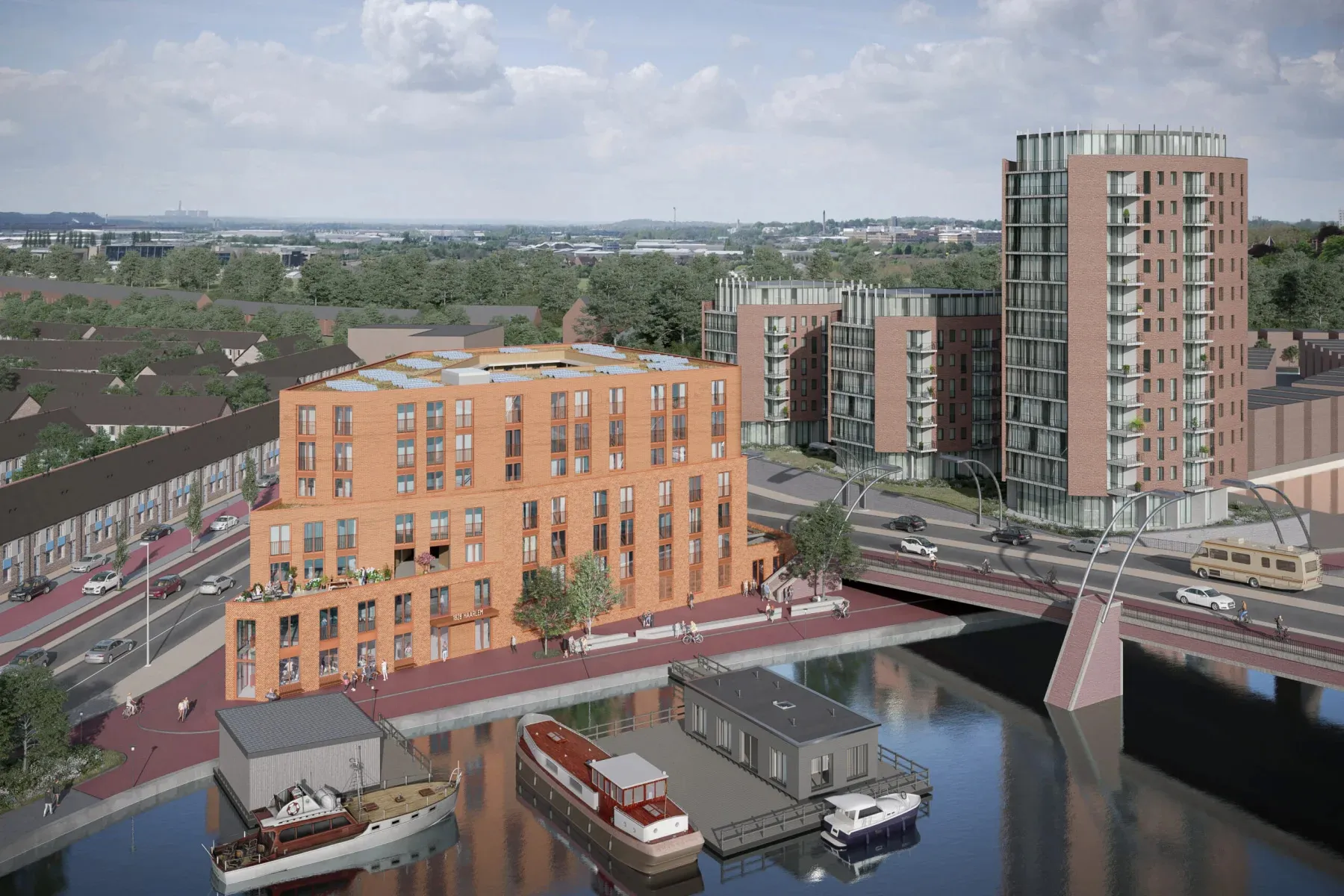 Luchtbeeld van een modern bakstenen wooncomplex langs een kanaal, met laag- en hoogbouw, balkons, voetgangers en fietsers op de omliggende straten en kleine boten in het water.