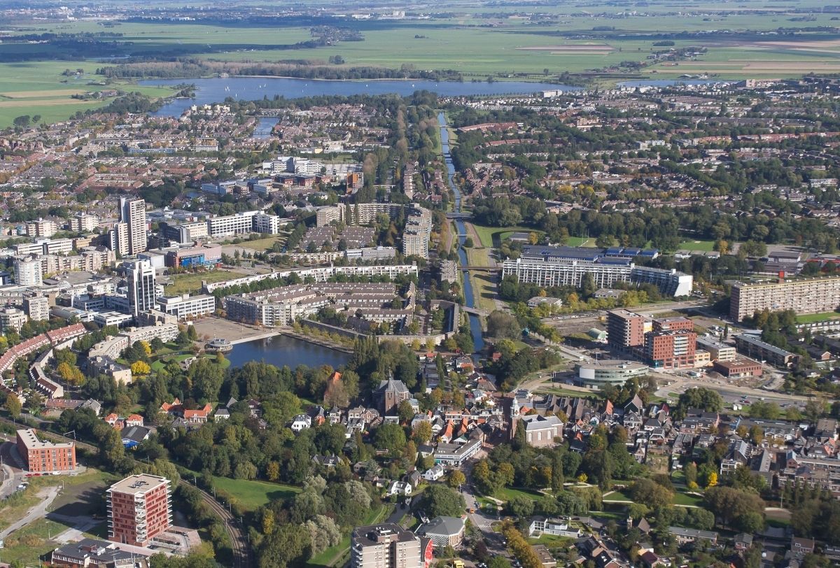 Luchtfoto van Zoetermeer met woonwijken, waterwegen, groengebieden en omliggend agrarisch landschap.