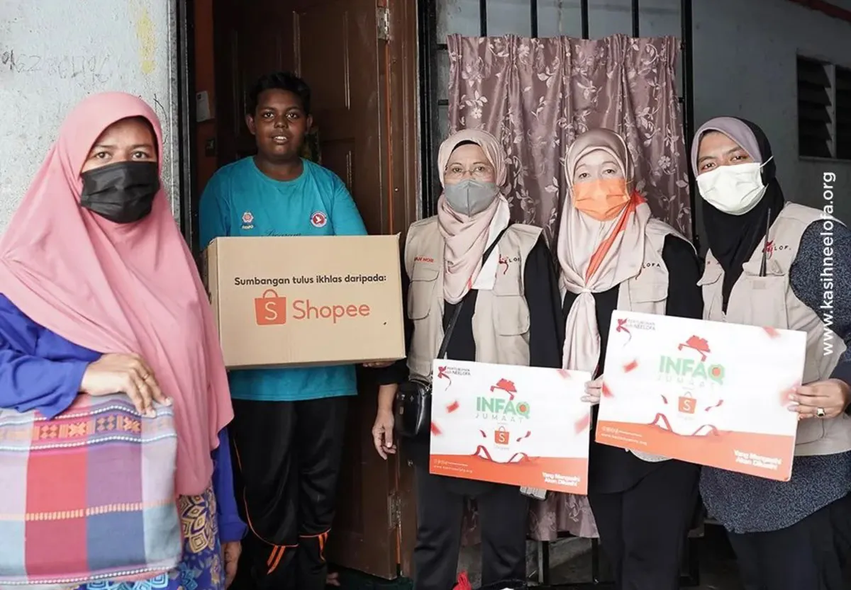 Group of five people, including three women wearing matching beige vests and masks, holding Shopee donation boxes during a charity event.