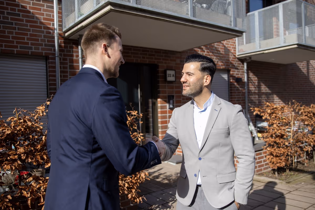 Gökhan Gül, Immobilienmakler in Bremen, beim Handschlag vor einem Wohnhaus