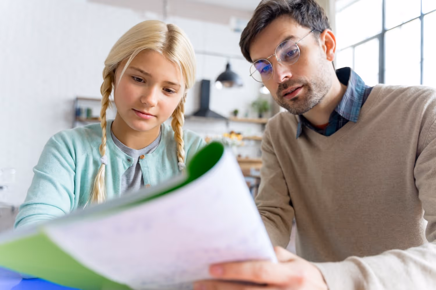 Vater unterstützt Tochter beim Lernen, während sie gemeinsam ein Buch betrachten.