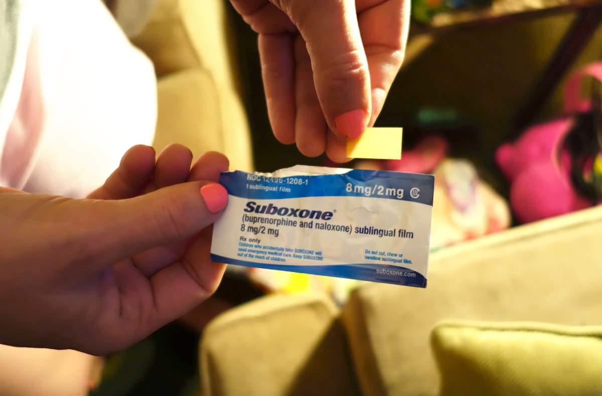 A person holding a single pill between their fingers, showcasing the medication clearly.