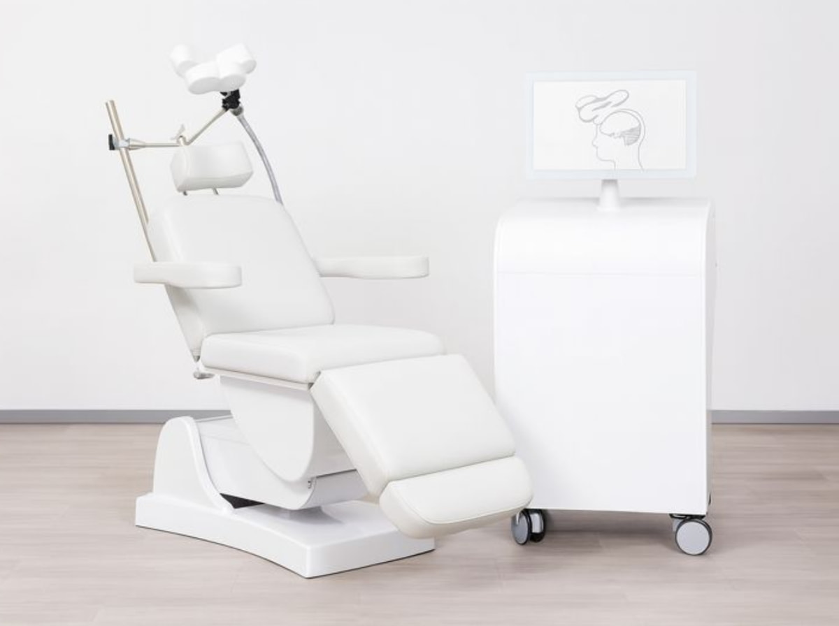 A white dental chair with a monitor positioned above it, ready for patient use in a dental office setting.  