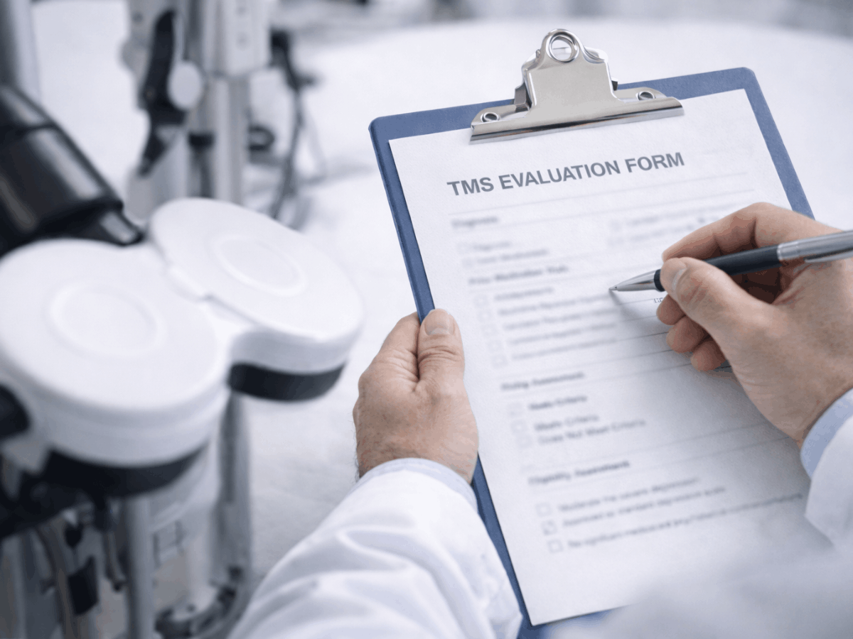 Clinician reviewing a transcranial magnetic stimulation (TMS) evaluation form beside a TMS device, documenting patient history and eligibility criteria for depression treatment.