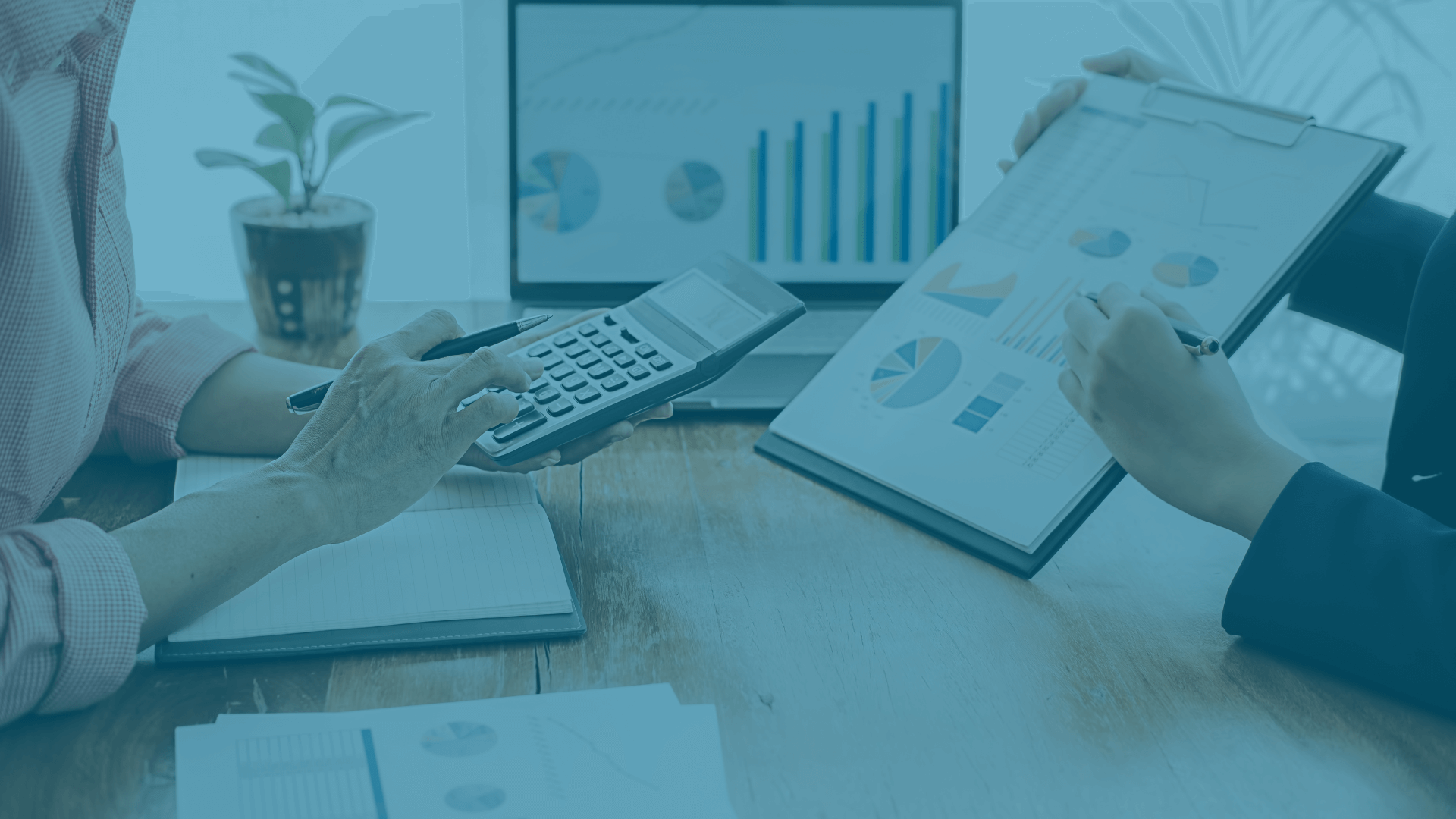 Two professionals pointing at a laptop screen while reviewing rate sheet margins.