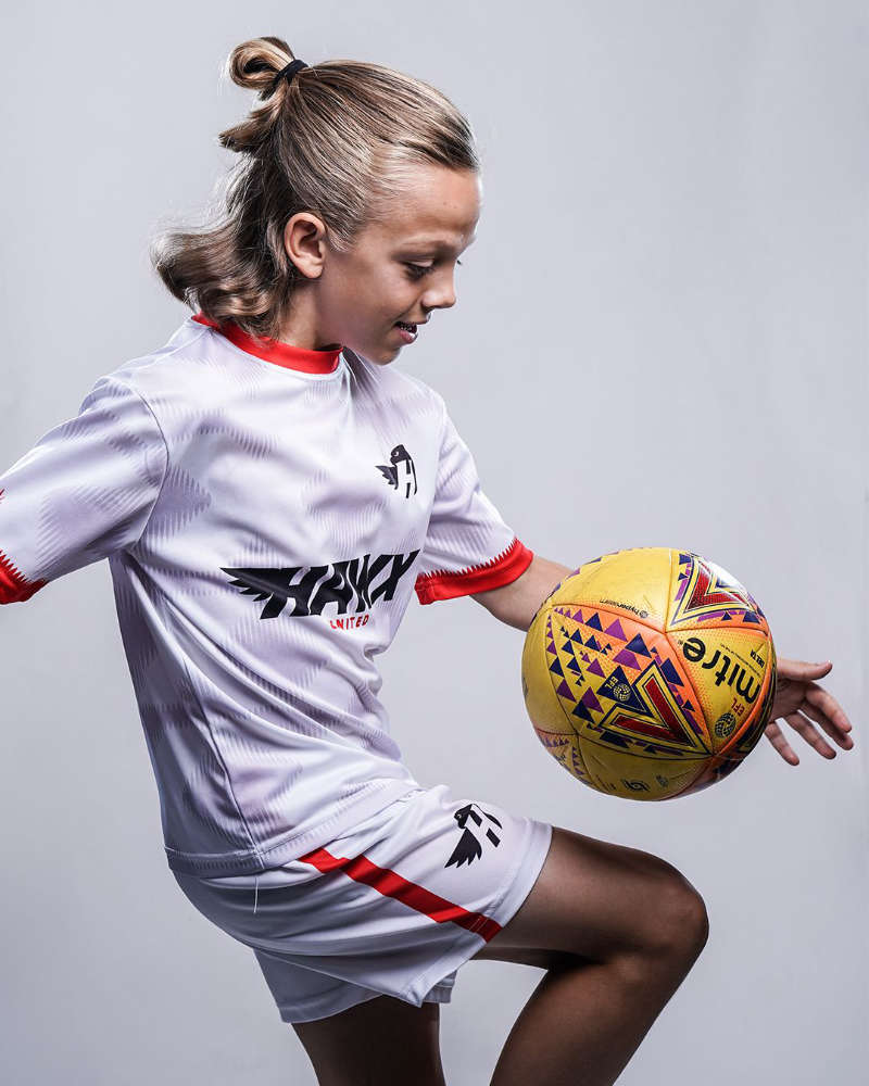 Four men standing closely together with arms around each other in a stadium with colorful seats in the background.