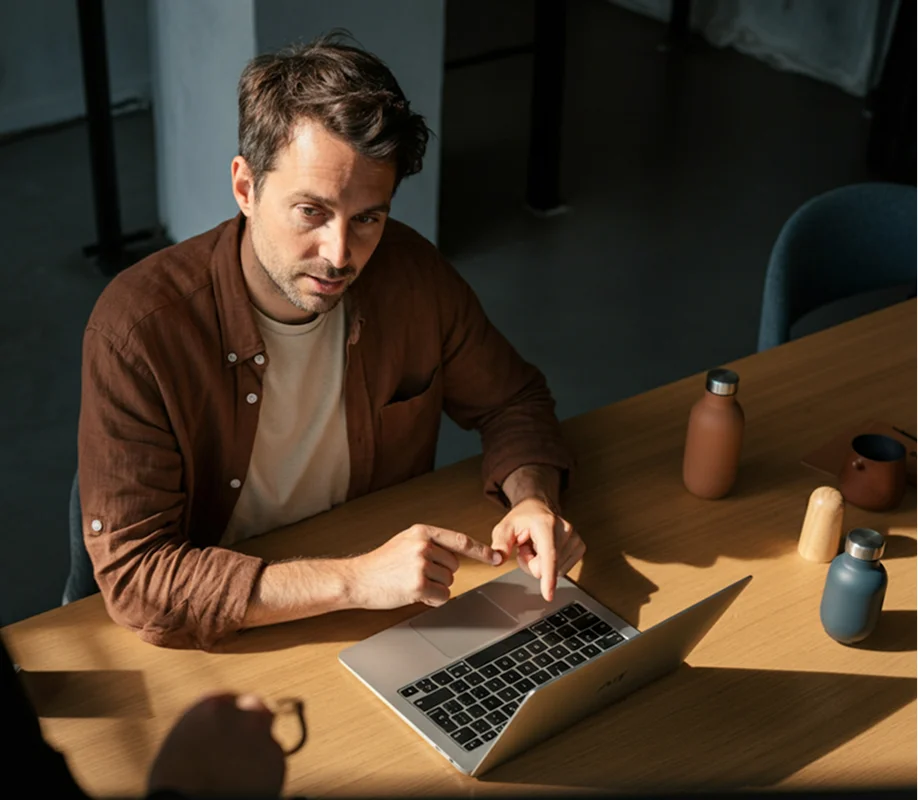 A woman and a man engaged in conversation in front of a whiteboard with business charts and diagrams.