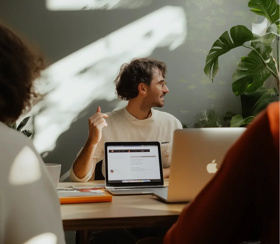 A woman and a man engaged in conversation in front of a whiteboard with business charts and diagrams.