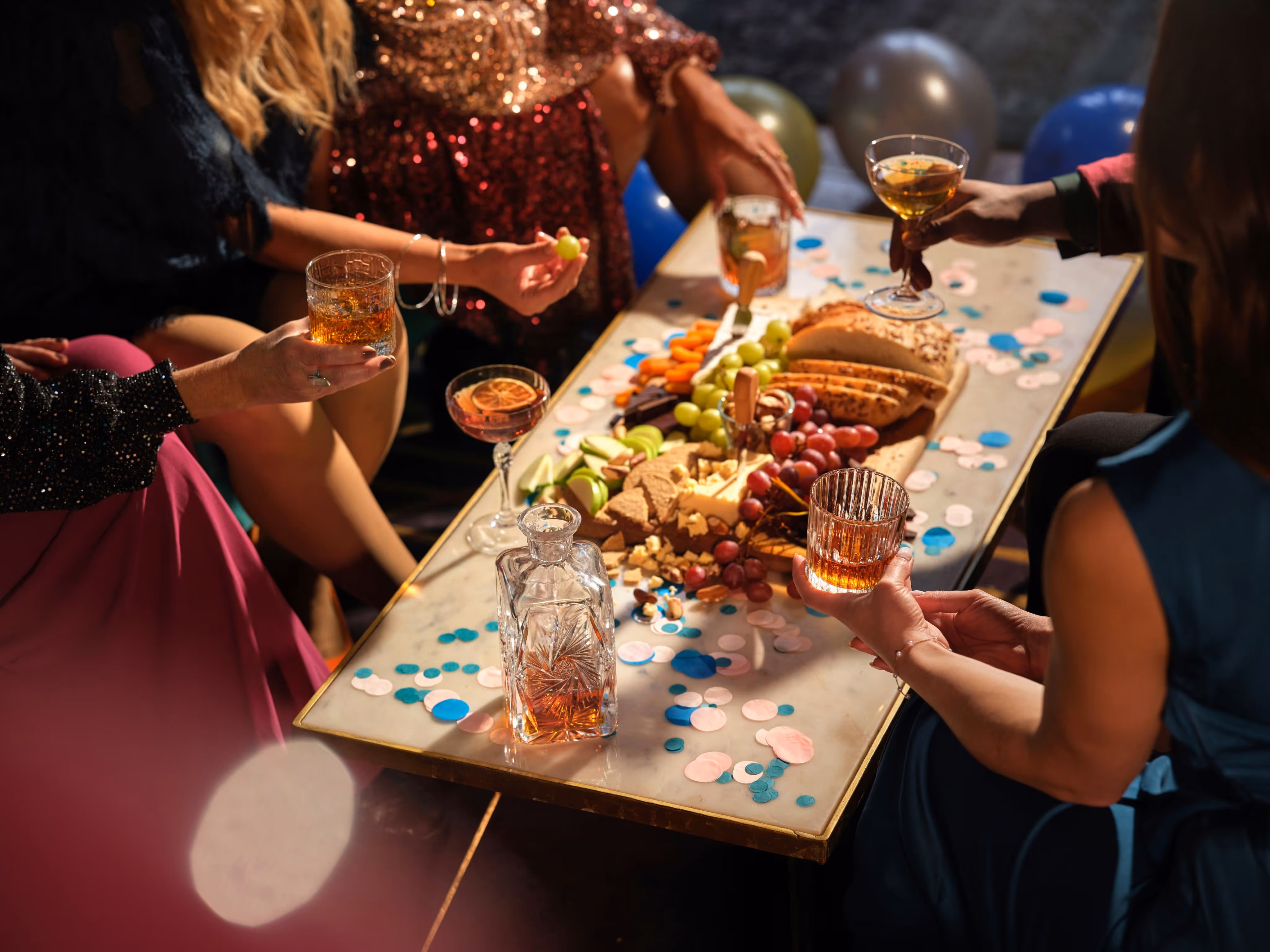 Friends enjoying festive drinks and appetisers at a Christmas party table with snacks and decorations.