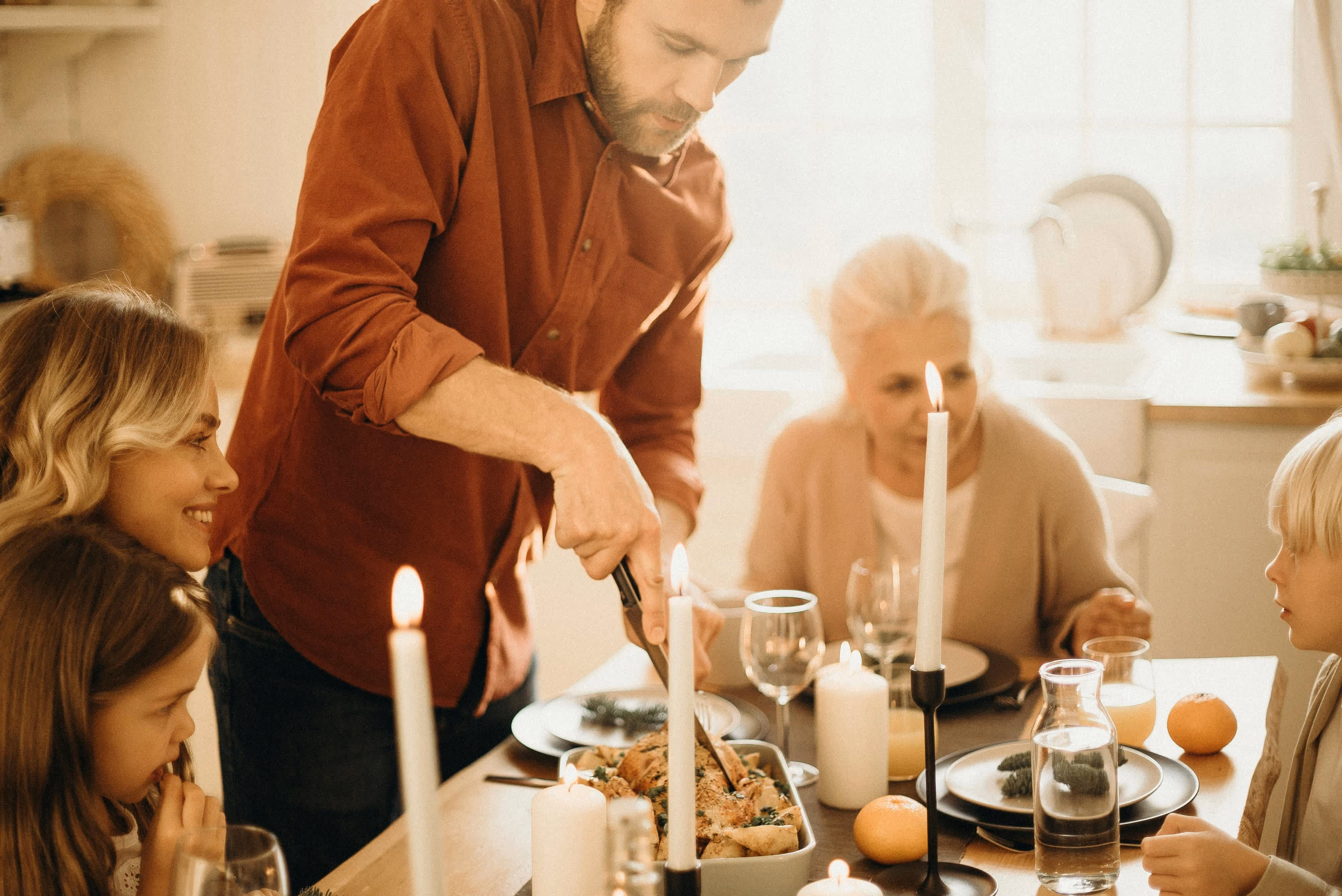 Family sharing a Christmas dinner with candles, roast meal, and festive decorations.