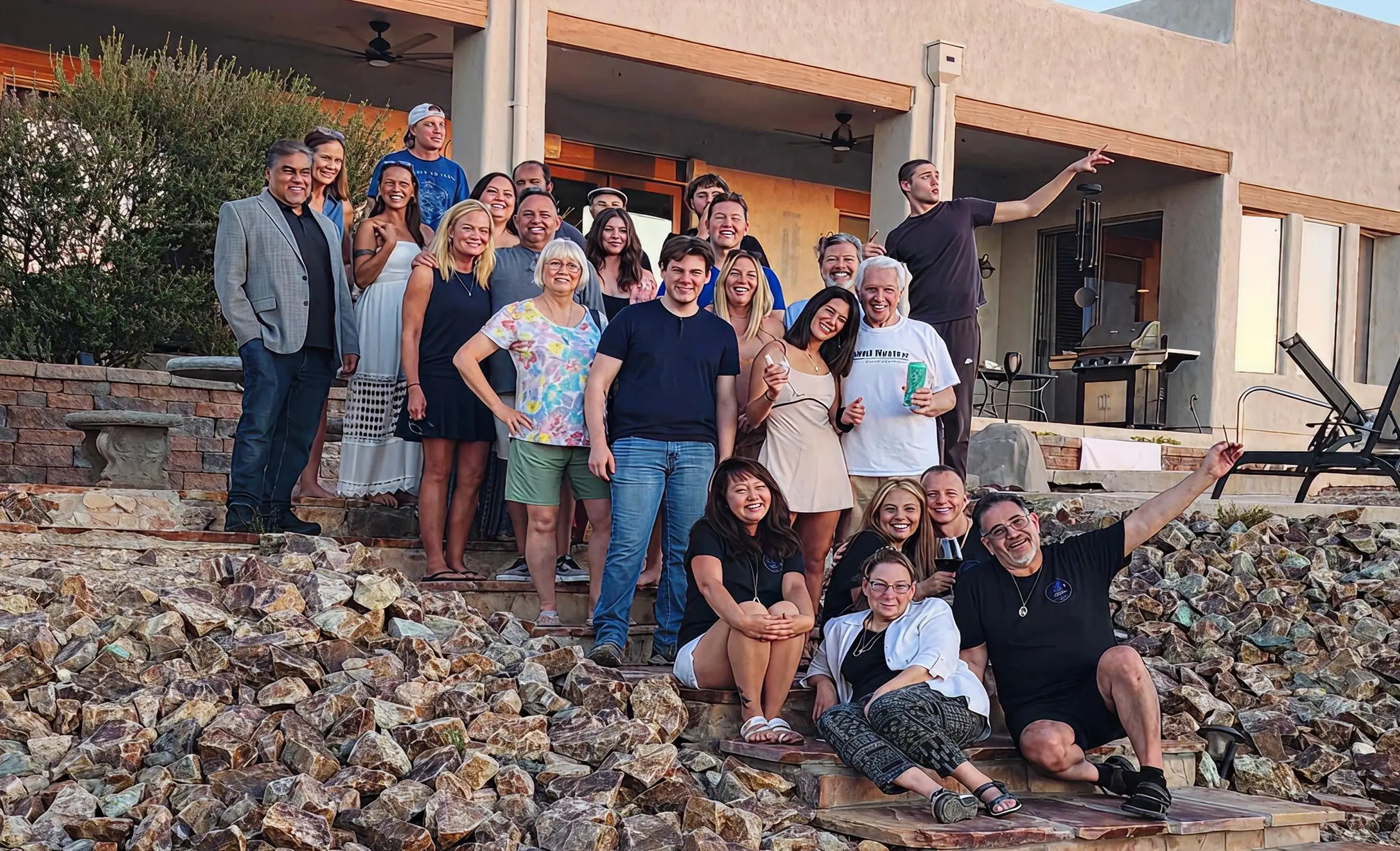 Group of people from a Mind Nexus Retreat smiling and posing together on stone steps outside a modern house during daytime.