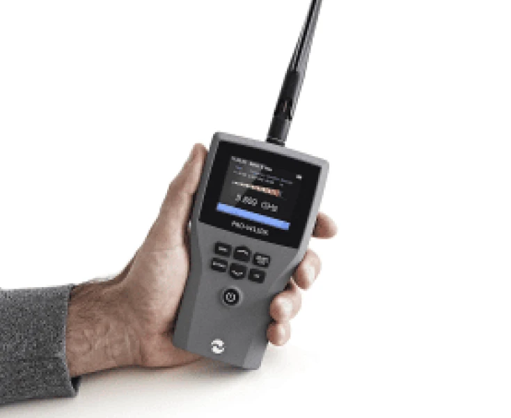 Hand holding a gray handheld RF signal detector.