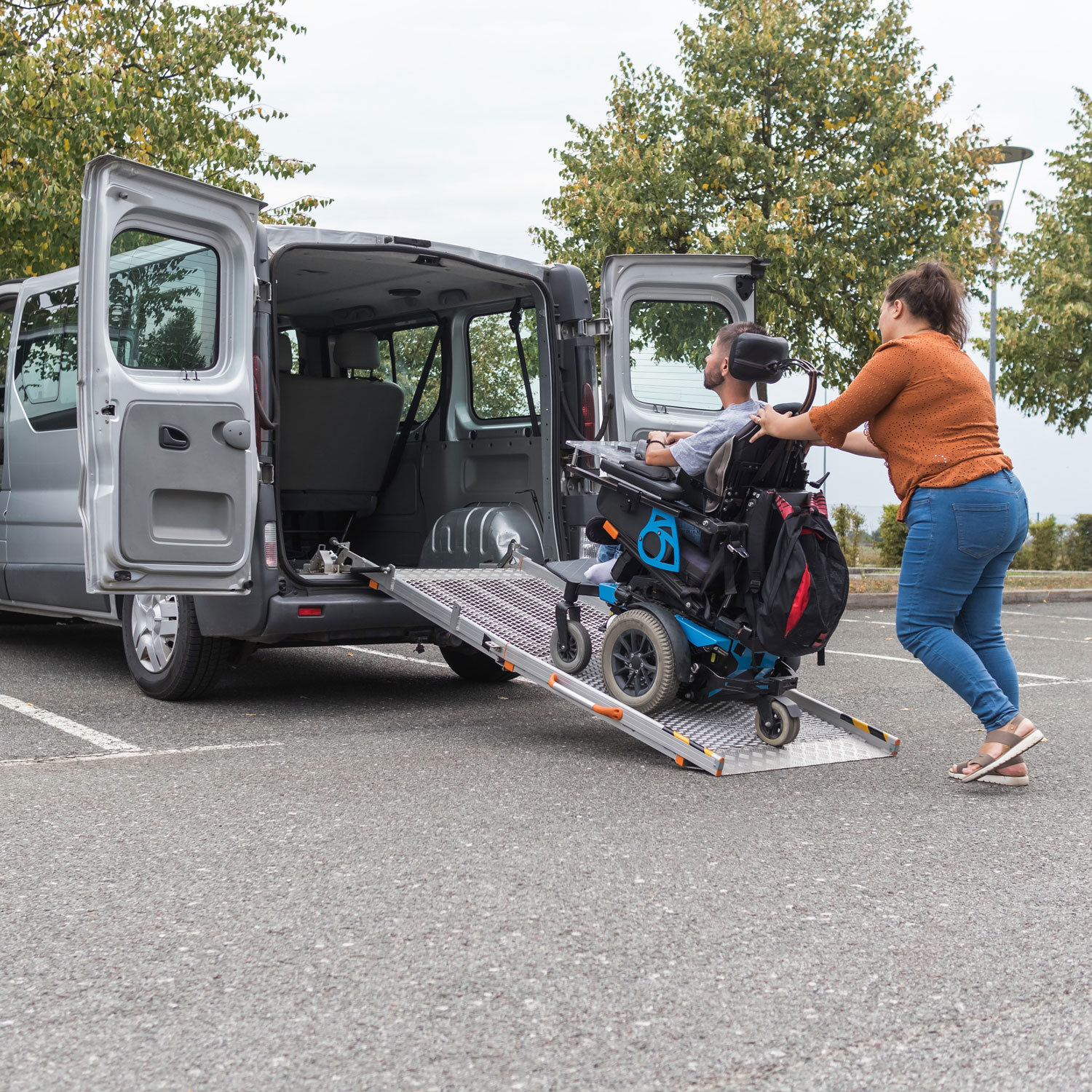A caregiver helps a man in a wheelchair into an accessible van.
