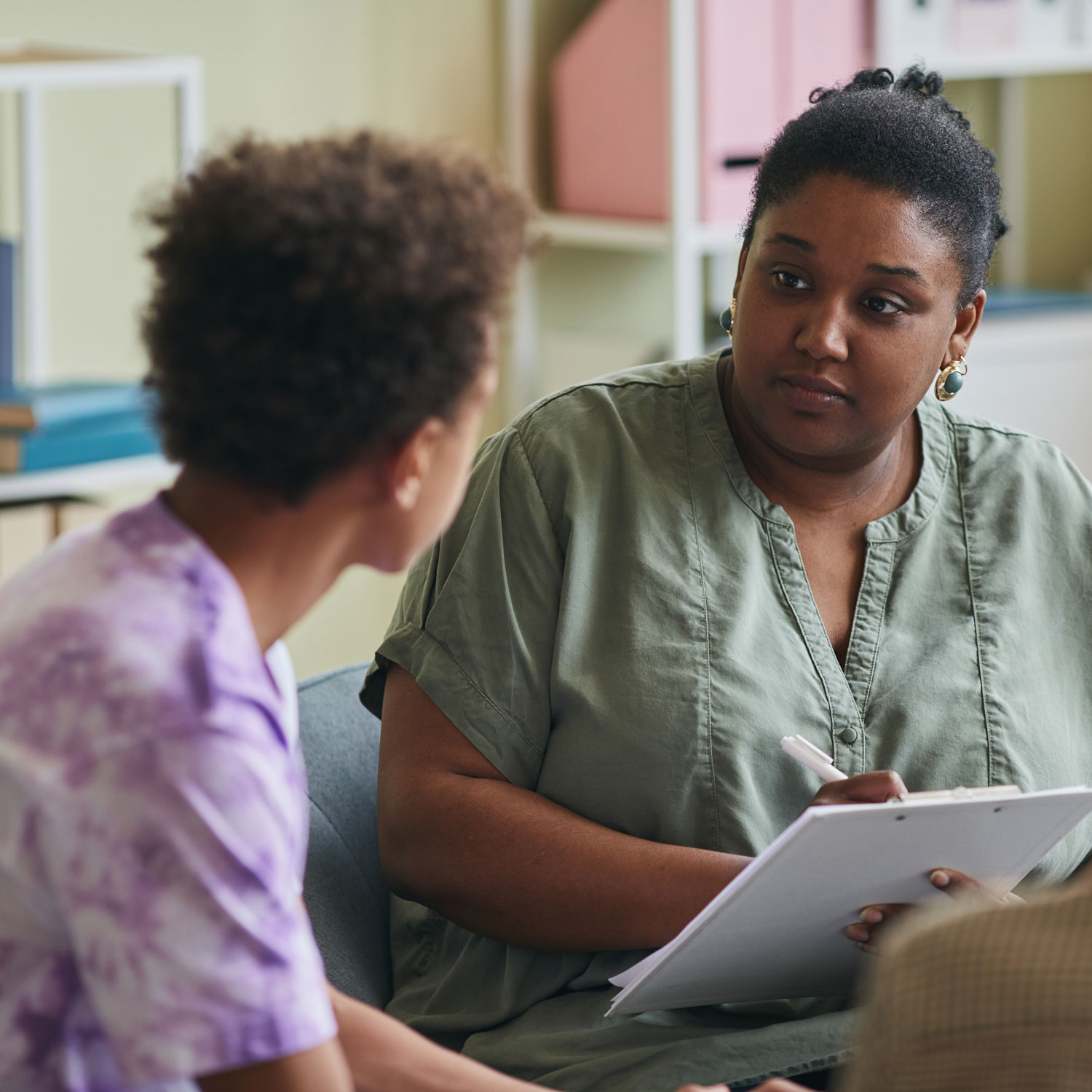 An adult therapist talks with a young patient.