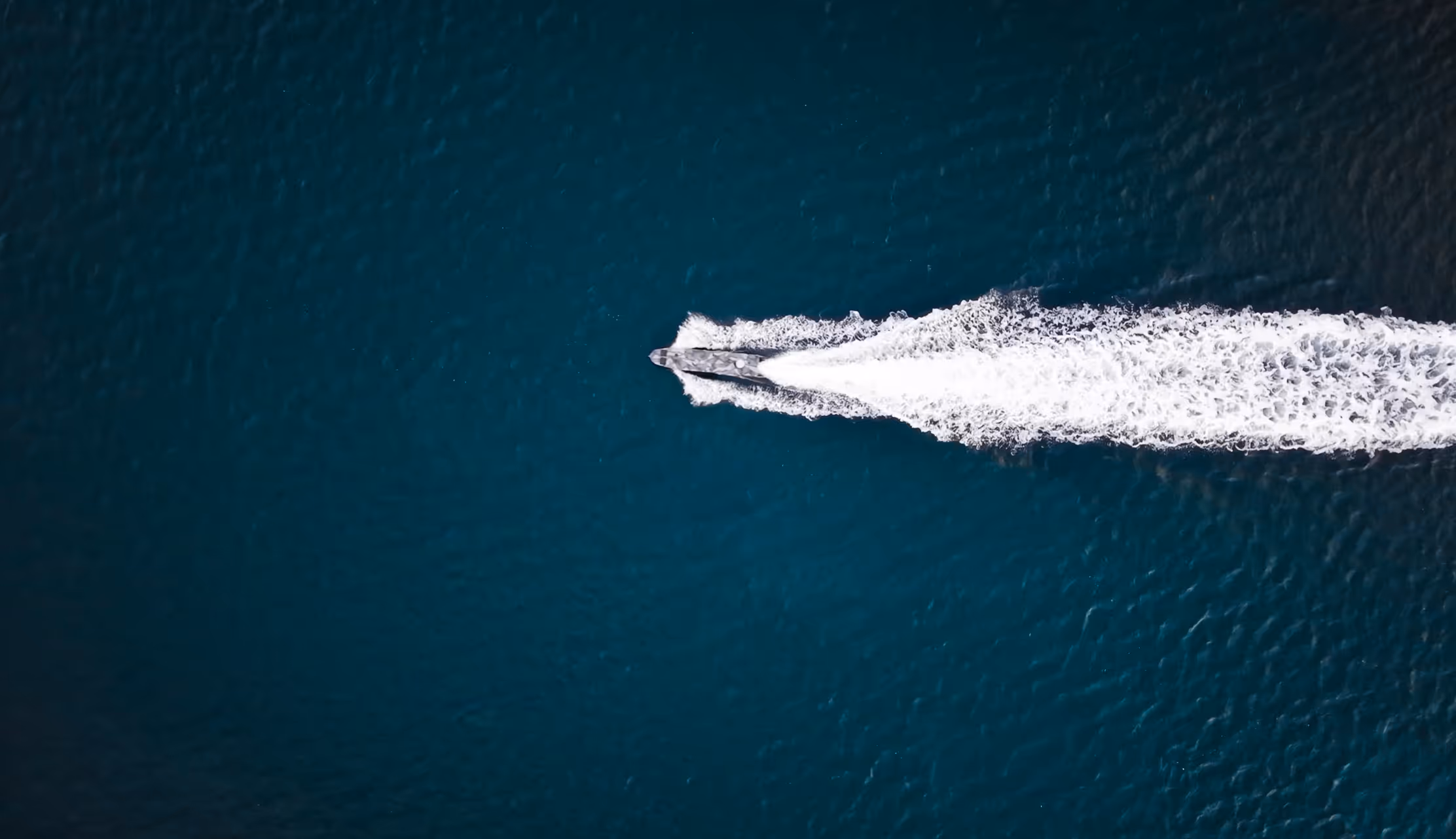 USV speeding across dark blue water leaving a white foamy wake behind.