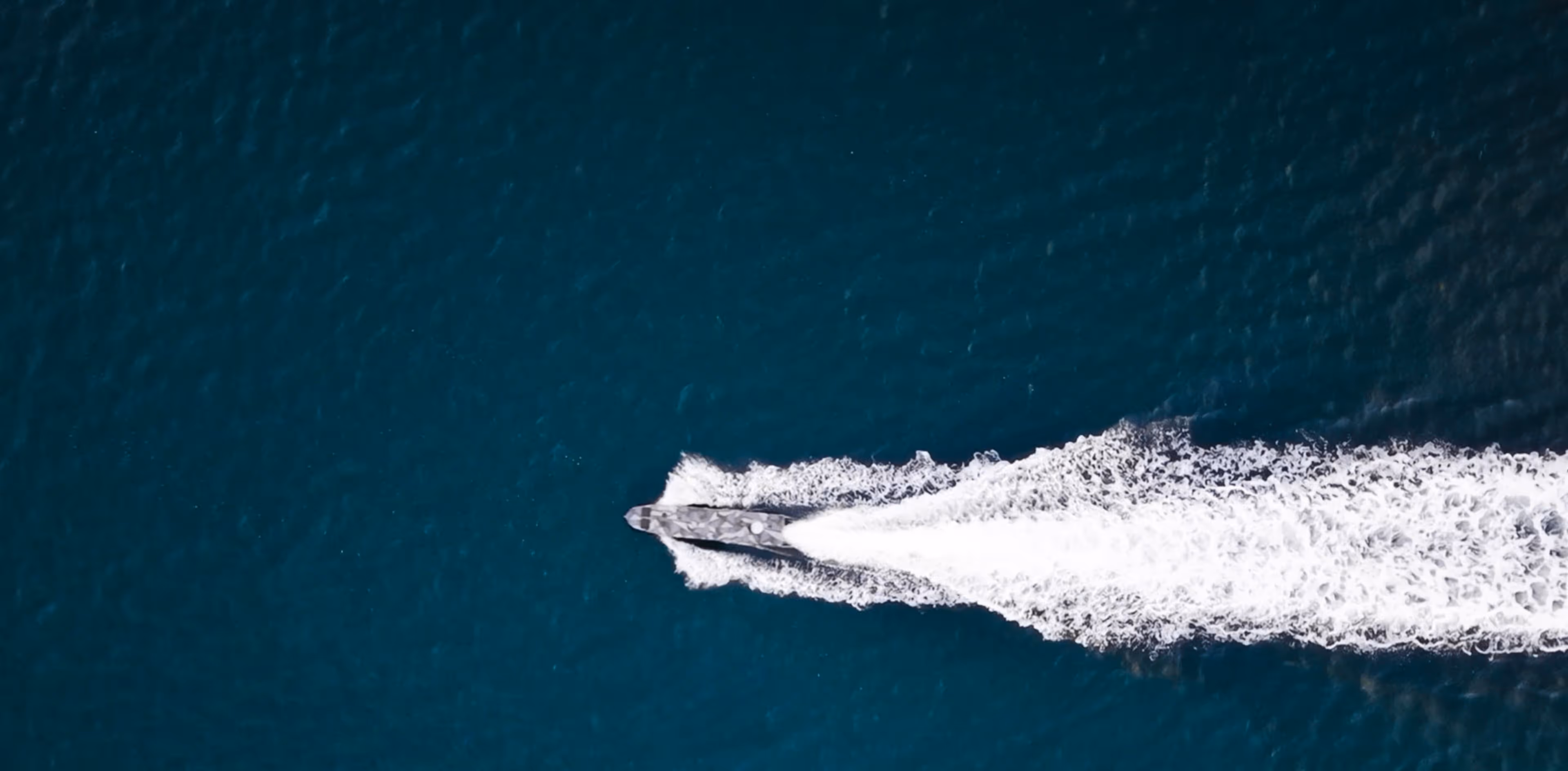 Arrow is traveling fast on dark blue water, creating a white foamy wake behind it.